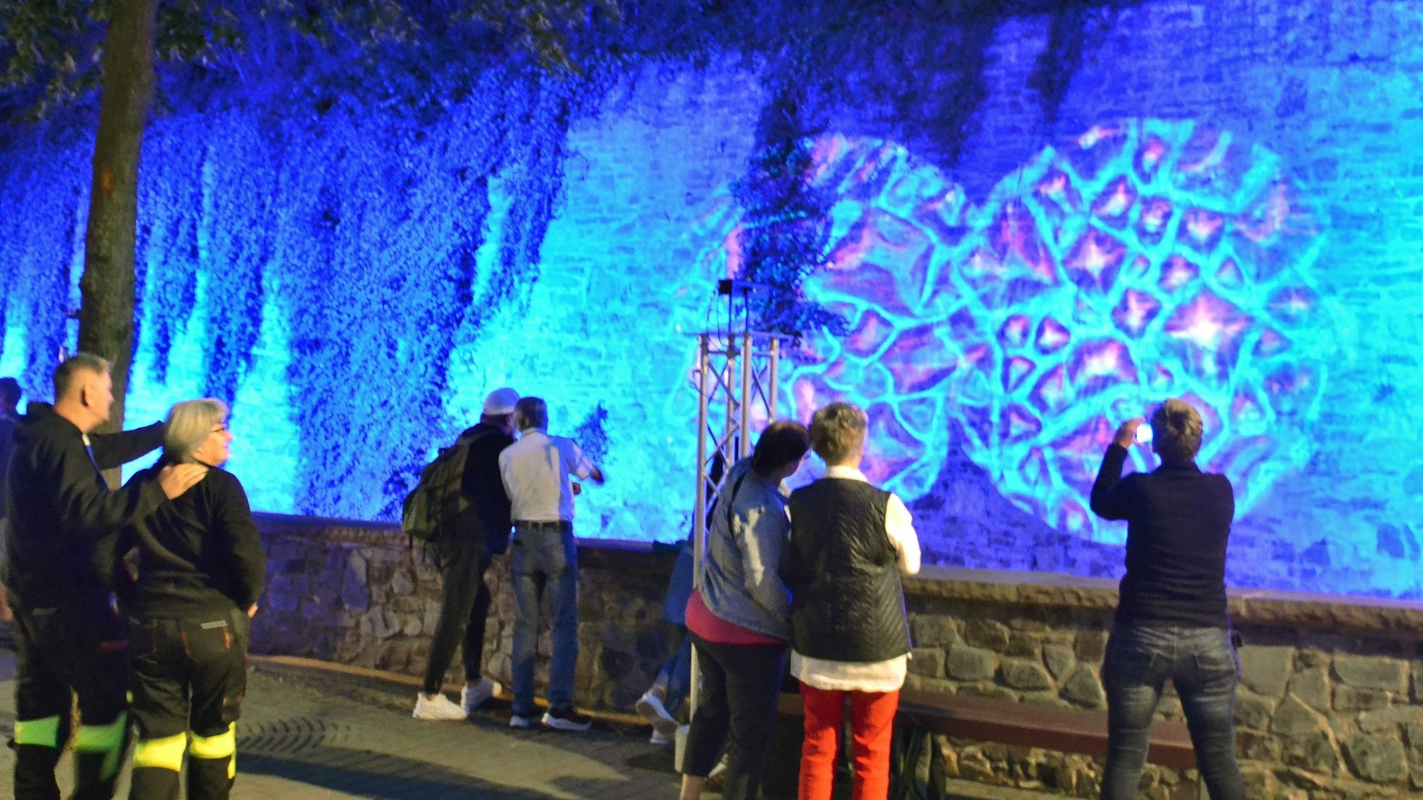 Zahlreiche Menschen betrachten eine Lichtinstallation an der Mauer der Erft in Bad Münstereifel.