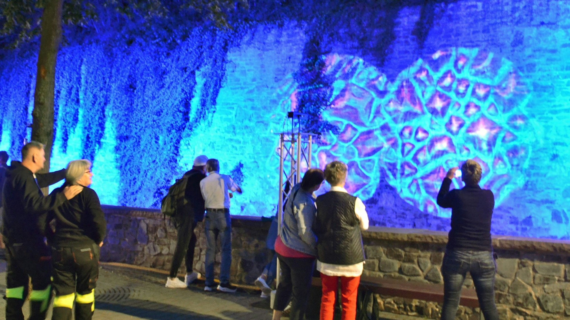 Zahlreiche Menschen betrachten eine Lichtinstallation an der Mauer der Erft in Bad Münstereifel.