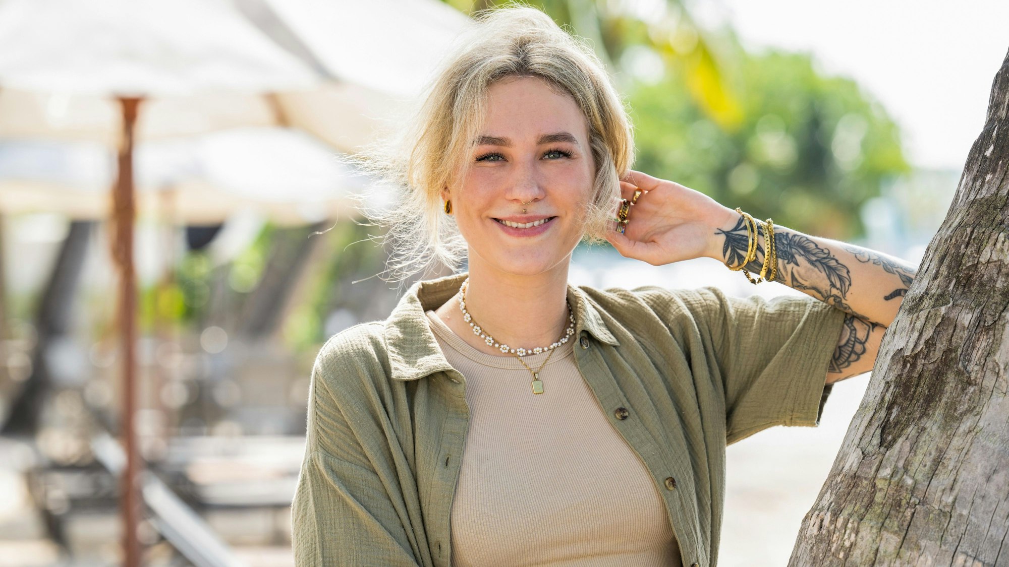 Die Kölnerin Christine ist Kandidatin der vierten Staffel Princess Charming auf RTL+. Auf dem Bild lehnt sie mit dem Arm an einem Baumstamm und lächelt in Richtung der Kamera.