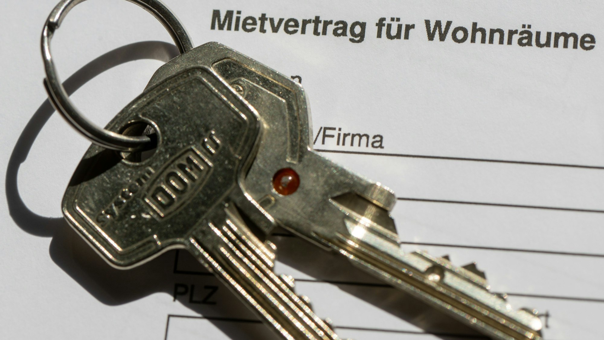 Ein Wohnungsschlüssel liegt auf einem Mietvertrag für eine Wohnung.