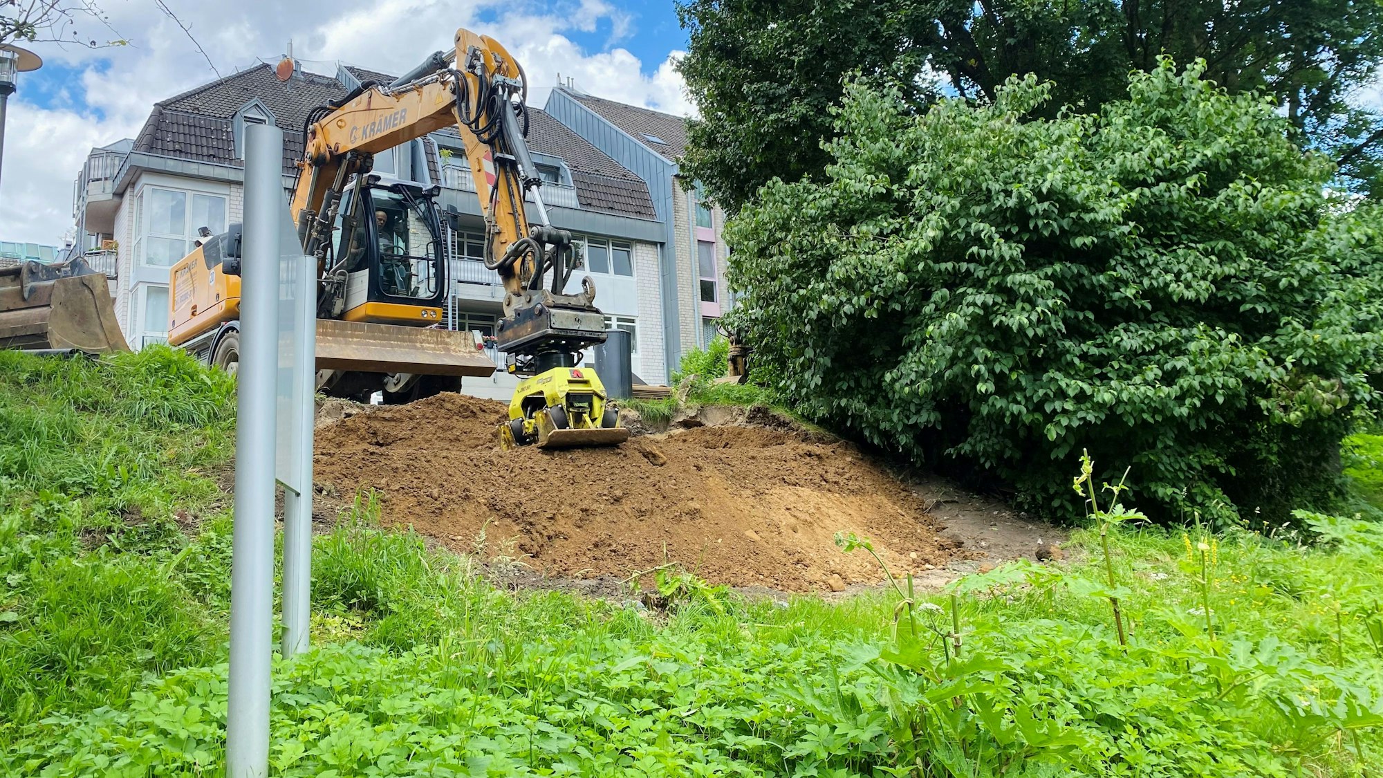 Ein Bagger verdichtet den aufgekippten Sand am Ufer der Wupper, dort, wo die Widerlager abgebrochen wurden.