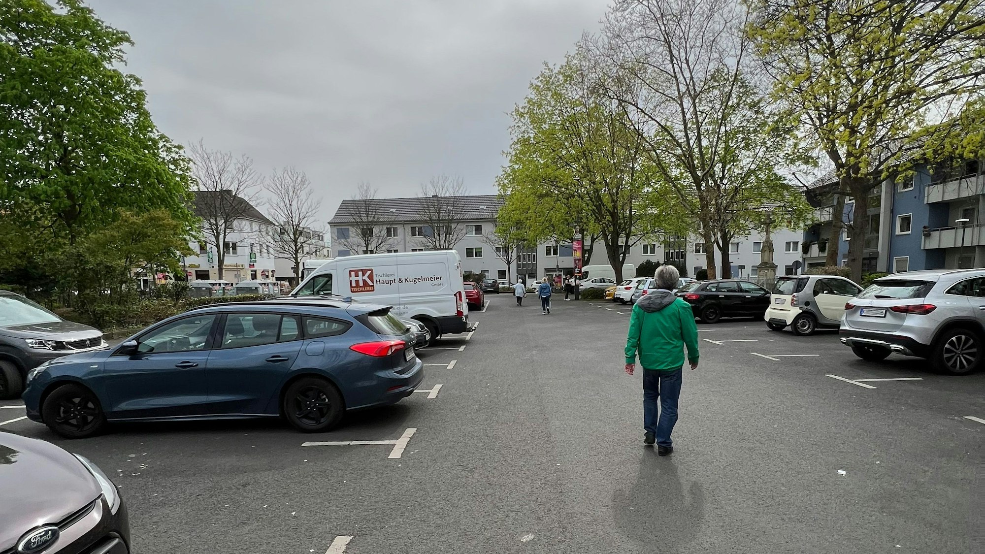 Eine Reihe an parkenden Autos, in der Mitte geht ein Fußgänger.