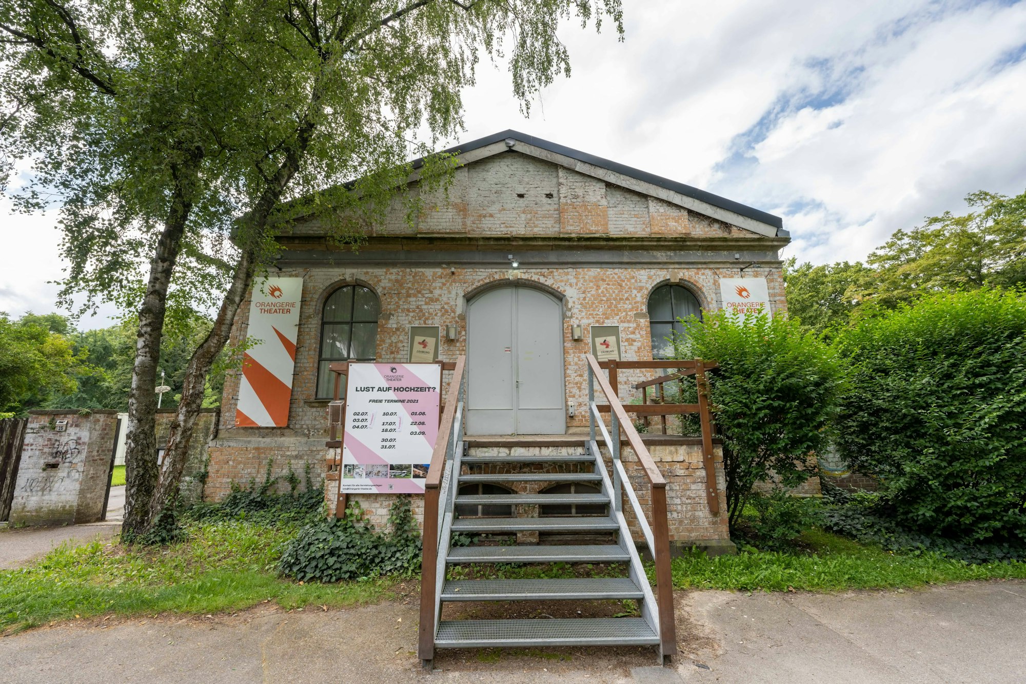 Eine Treppe führt zum Gebäude herauf, das durch die leicht orange gefärbten Backsteine einen altertümlichen Eindruck macht.