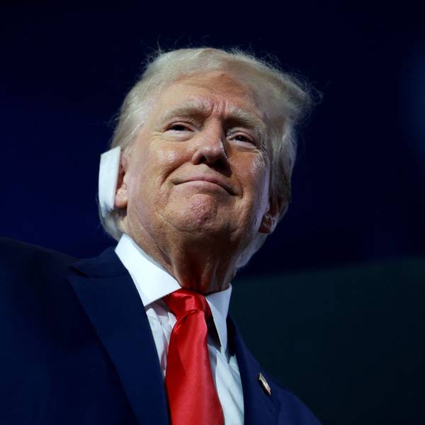 Vor dunklem Hintergrund hebt sich das lächelnde Gesicht Donald Trumps ab. Über dem rechten Ohr trägt er einen Verband, Zeugnis der Verletzung durch ein Attentat während einer Wahlkampfveranstaltung am 13. Juli.
