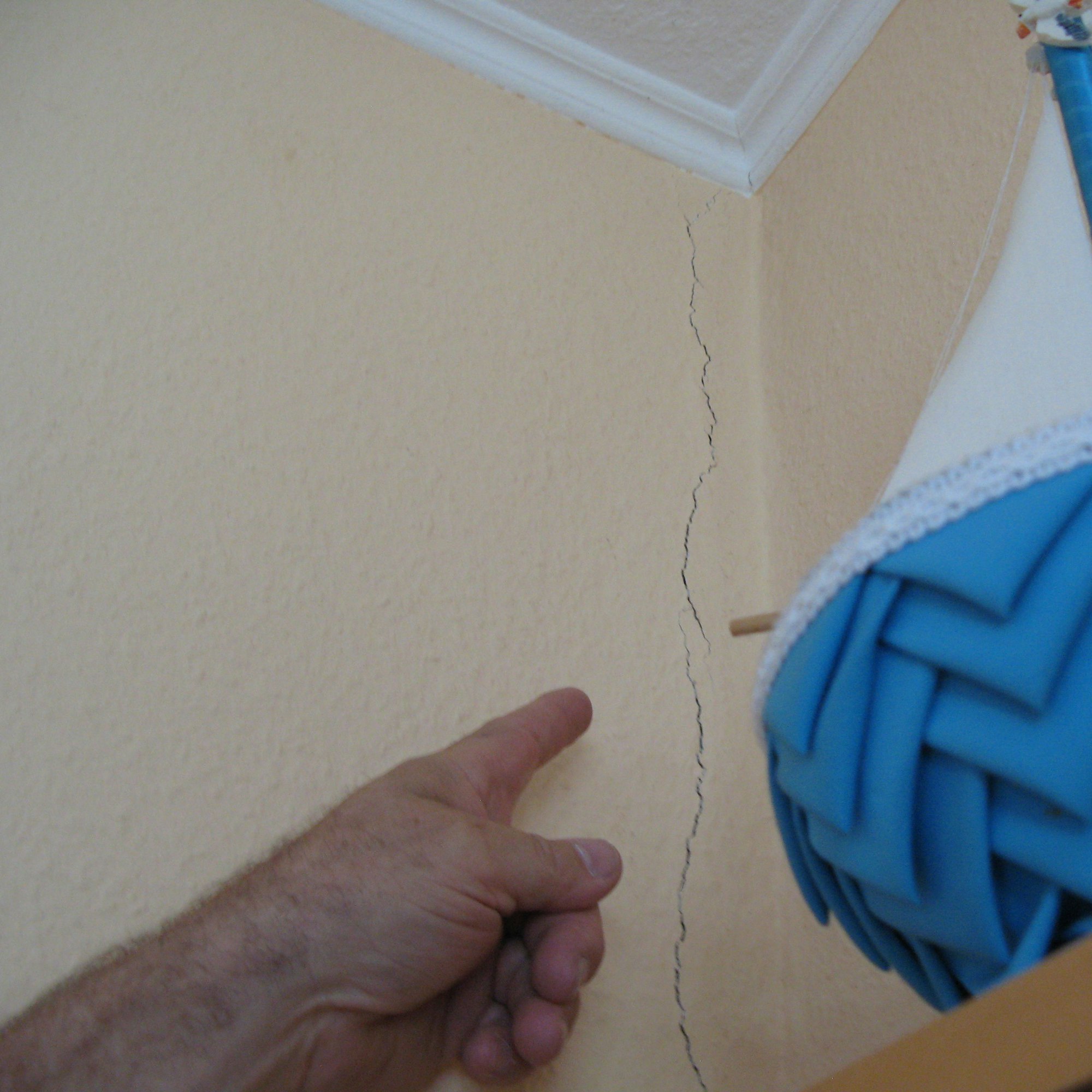 Eine Hand zeigt auf einen Riss an einer Innenwand.