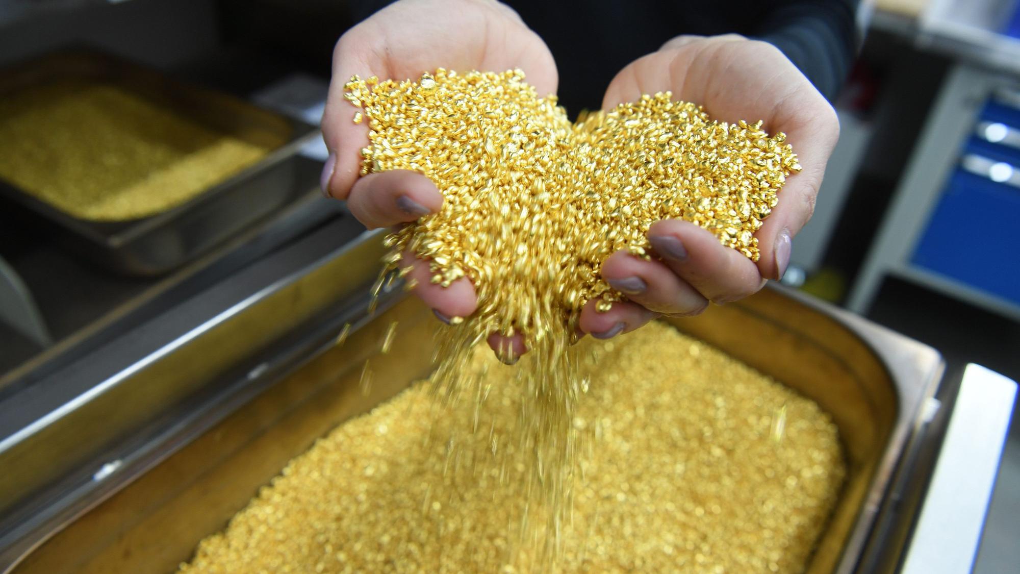 ARCHIV - 28.04.2017, Baden-Württemberg, Pforzheim: Goldgranulat, das einen Feingoldgehalt von 99,99 Prozent hat, rieselt bei der Firma Allgemeine Gold- und Silberscheideanstalt AG Agosi in Pforzheim (Baden-Württemberg) durch zwei Hände. In Köln ist Goldgranulat im Wert von einer Million Euro gestohlen worden. (zu dpa: «Gold-Diebstahl am Kölner Flughafen: Gesuchter Mann ermittelt») Foto: Uli Deck/dpa +++ dpa-Bildfunk +++
