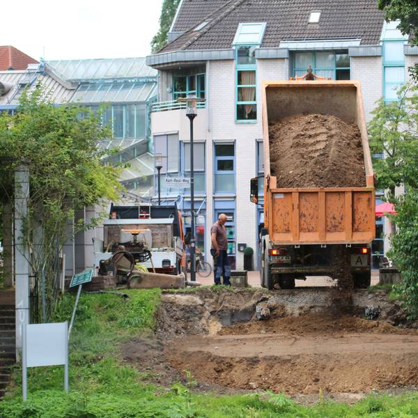 Ein Lastwagen kippt Sand auf die Böschung.
