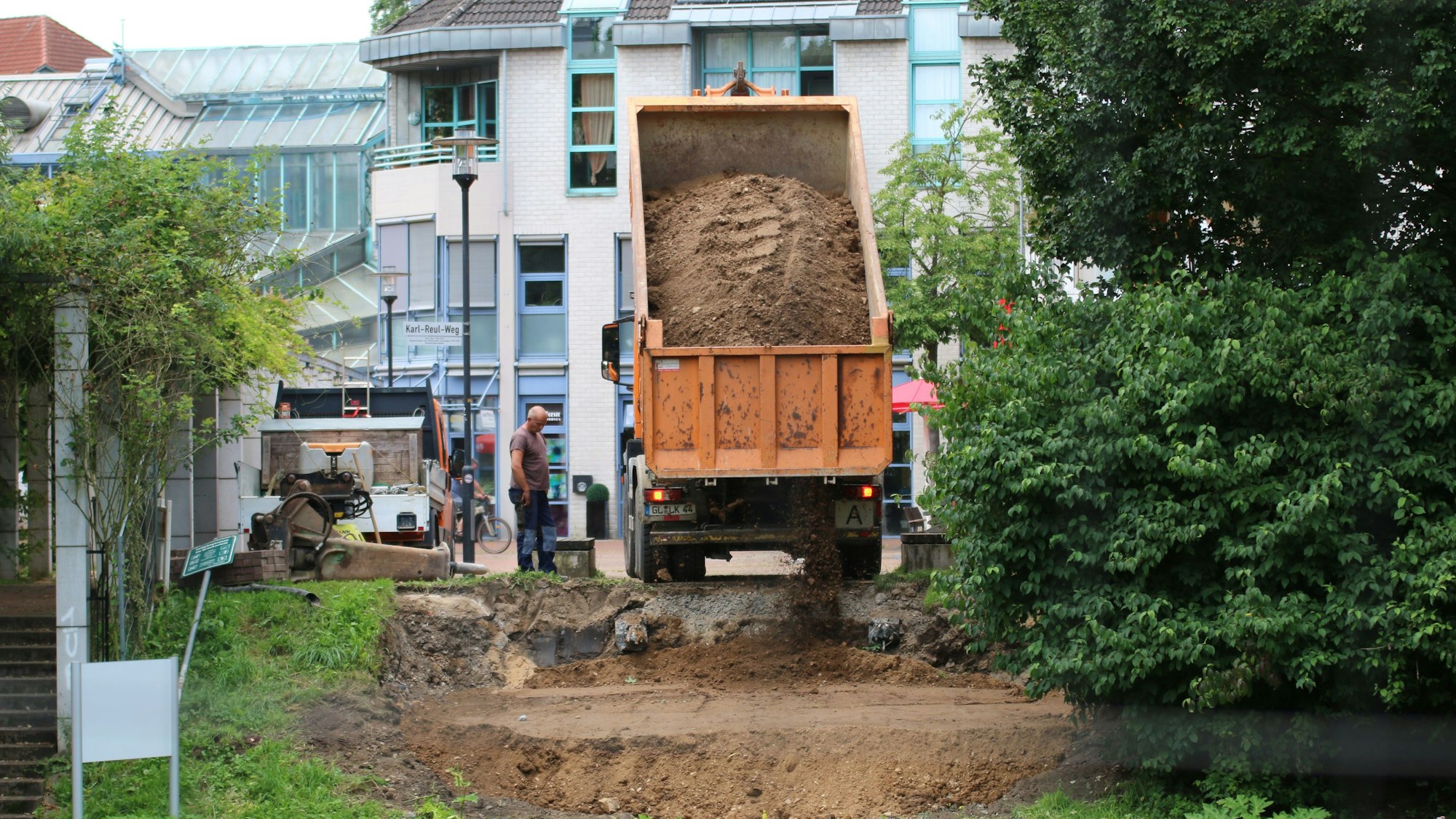 Ein Lastwagen kippt Sand auf die Böschung.