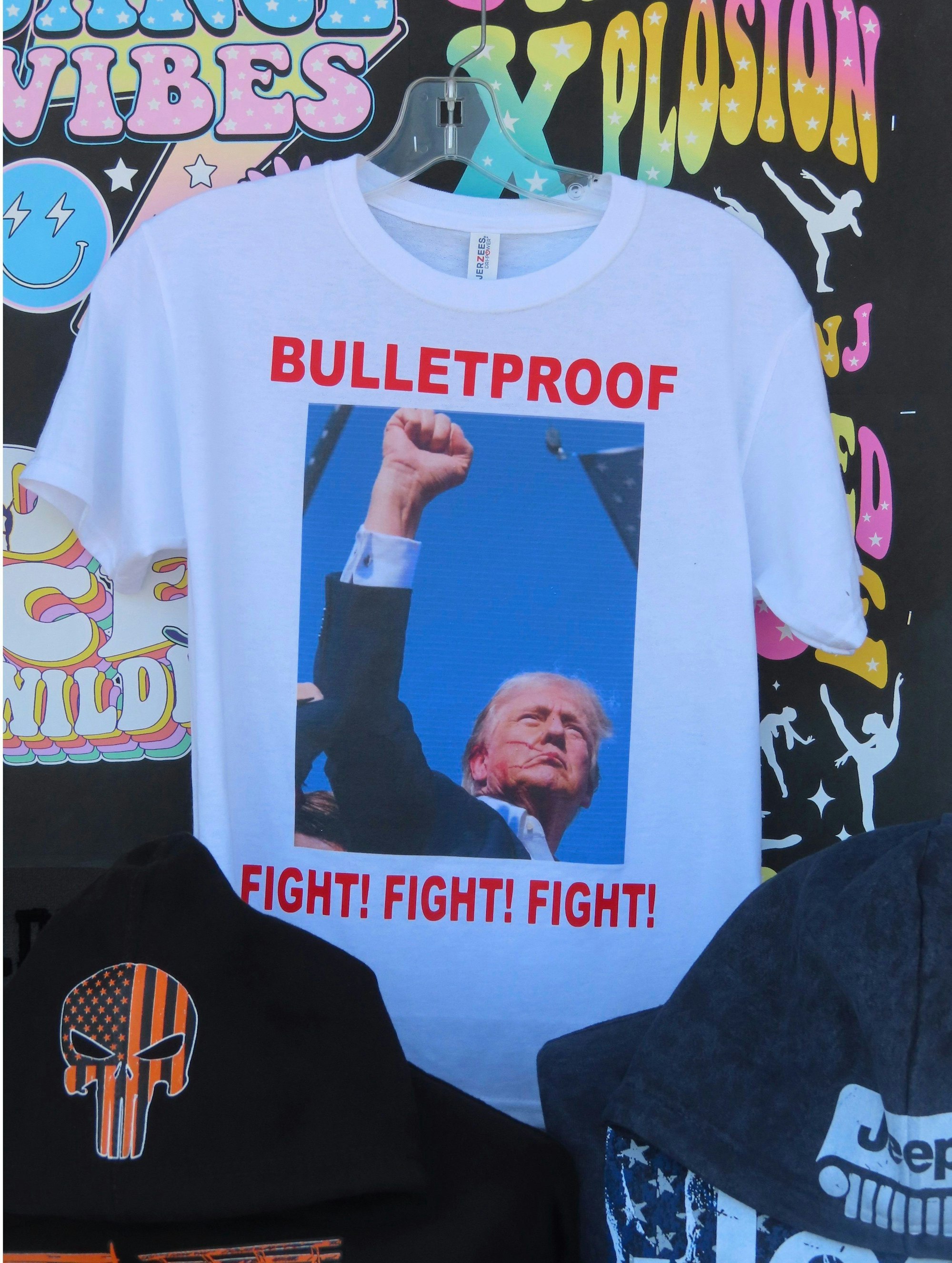 15.07.2024, USA, Wildwood: T-Shirts, die sich auf das Attentat auf den ehemaligen US-Präsidenten Donald Trump beziehen, fanden am 15. Juli 2024, weniger als 48 Stunden nach dem Vorfall, auf der Strandpromenade in Wildwood, N.J., reißenden Absatz. Foto: Wayne Parry/AP +++ dpa-Bildfunk +++