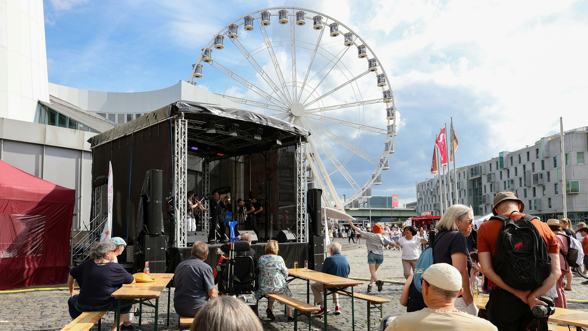 Zuschauer sitzen auf Bierbänken vor einer Bühne am Schokoladenmuseum