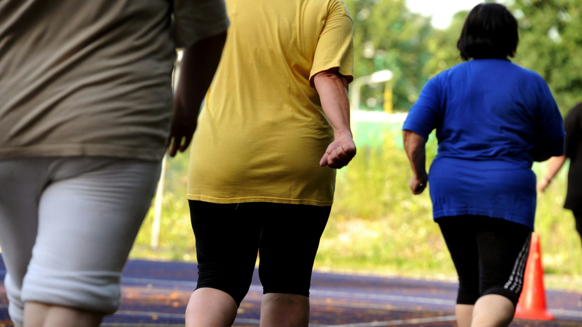 Übergewichtige Frauen und Männern machen im Rahmen eines bundesweiten Abnehmprogramms auf einem Sportplatz in Leipzig Ausdauerübungen.