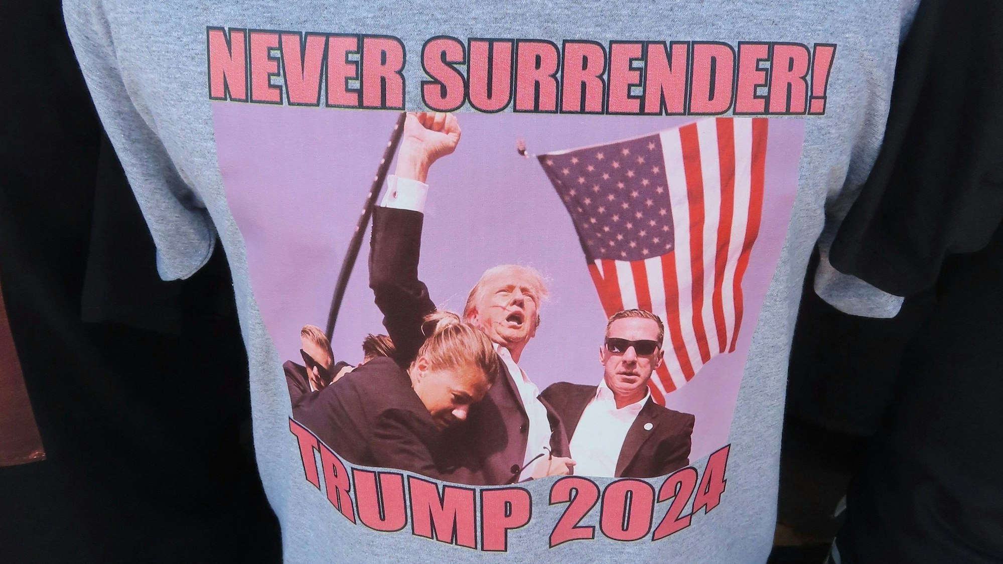 15.07.2024, USA, Wildwood: T-Shirts, die sich auf das Attentat auf den ehemaligen US-Präsidenten Donald Trump beziehen, fanden am 15. Juli 2024, weniger als 48 Stunden nach dem Vorfall, auf der Strandpromenade in Wildwood, N.J., reißenden Absatz. Foto: Wayne Parry/AP +++ dpa-Bildfunk +++