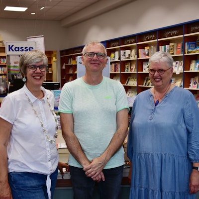 Ein Mann und zwei Frauen stehen in einer Buchhandlung.