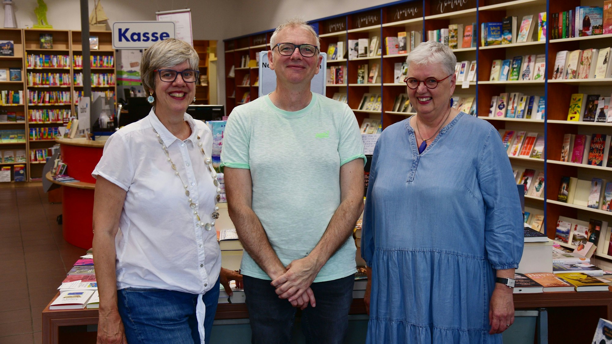 Ein Mann und zwei Frauen stehen in einer Buchhandlung.