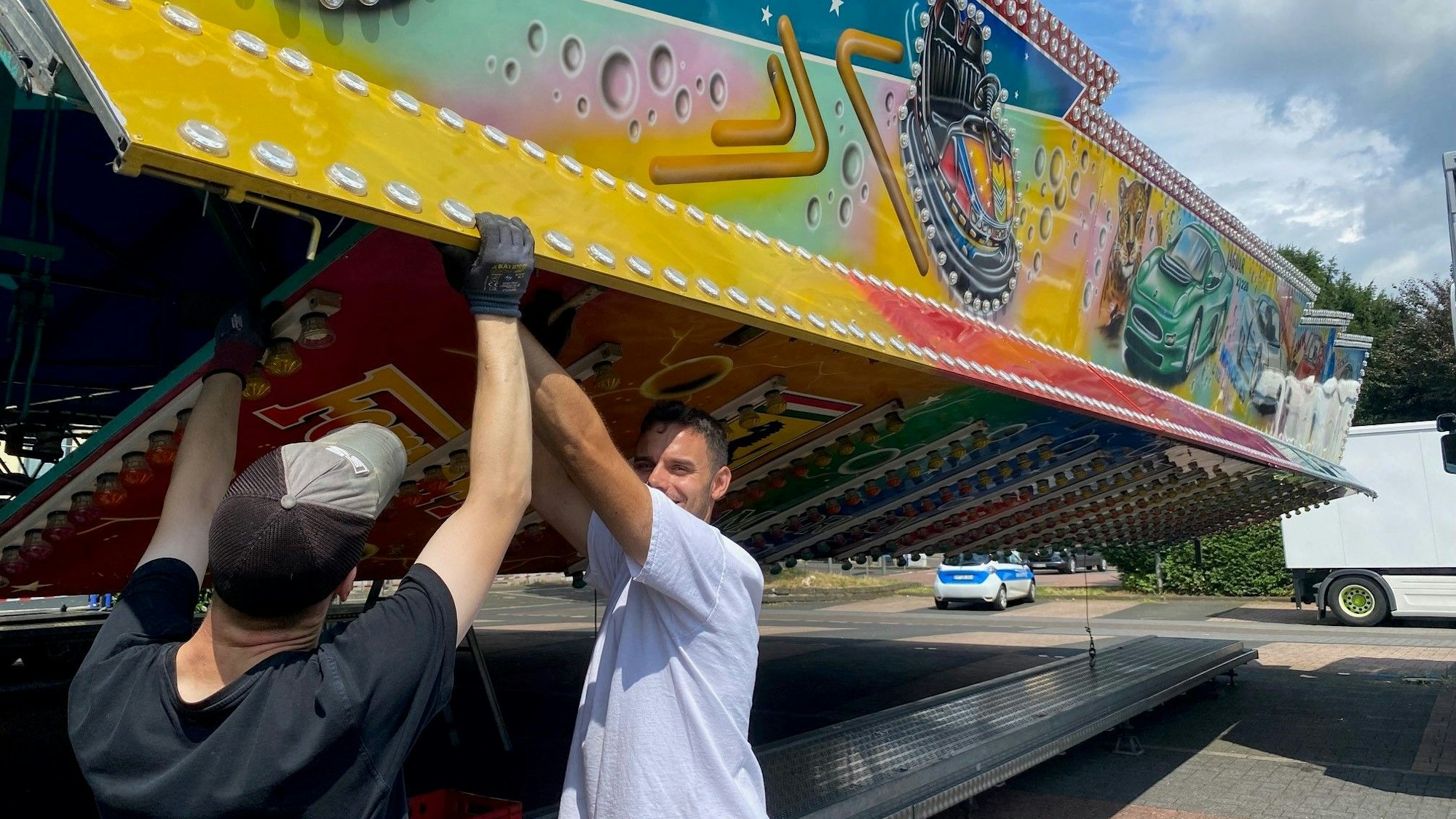 Zu sehen sind zwei Schausteller, die den Autoscooter aufbauen.