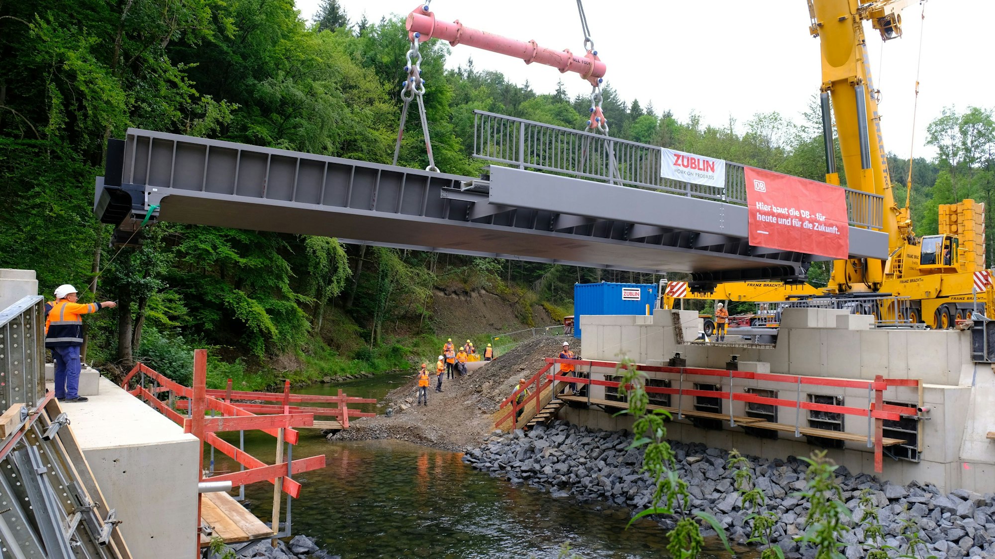 Wiederaufbau der Eifelstrecke: Im Bereich An der Spick bei Sötenich wird eine vorgefertigte Dickblech-Trogbrücke mit einem Kran eingehoben. Ab dem Jahr 2025 sollen dort wieder Züge über die Urft rollen.