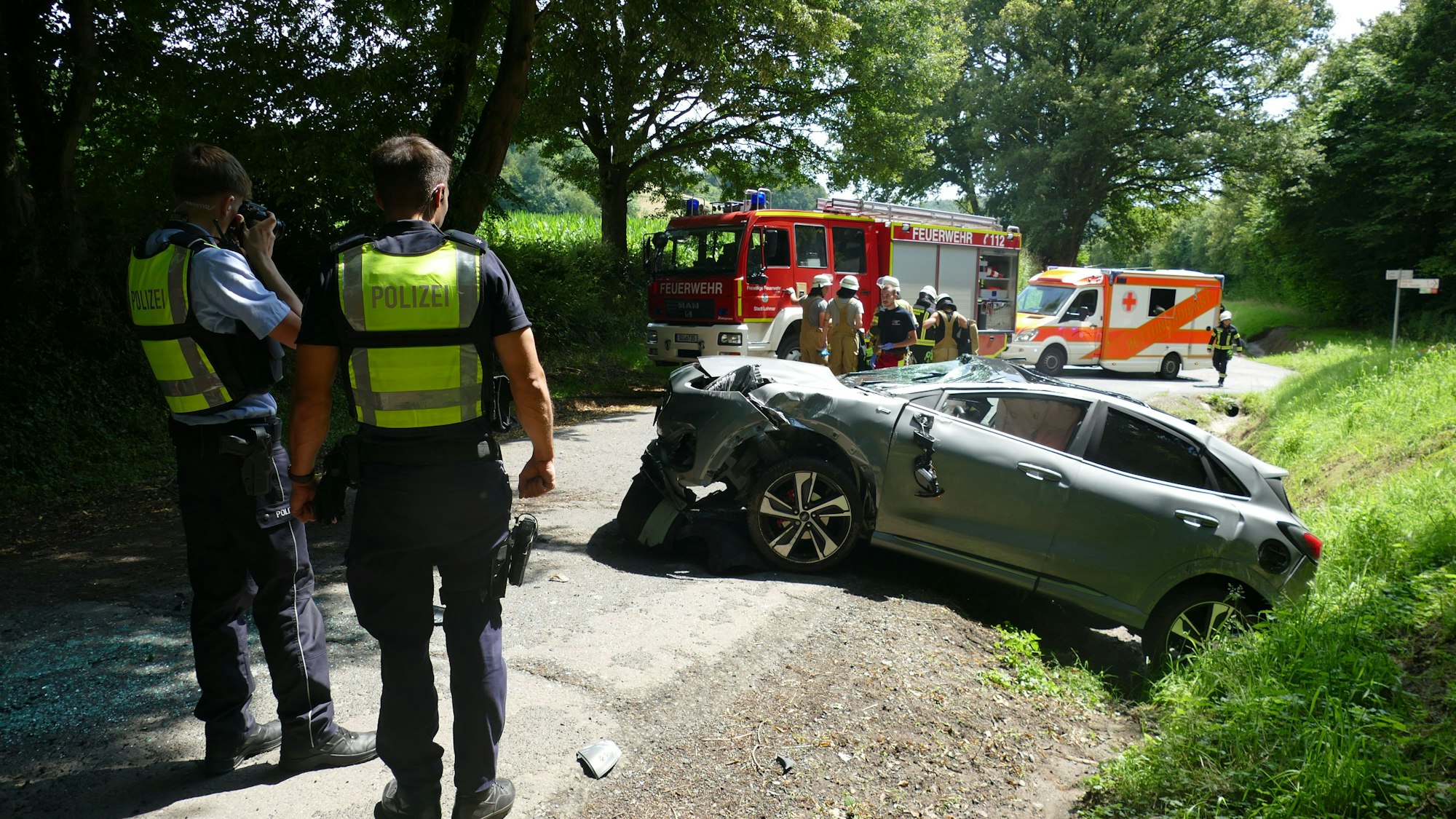 Polizisten stehen vor einem Unfallauto.