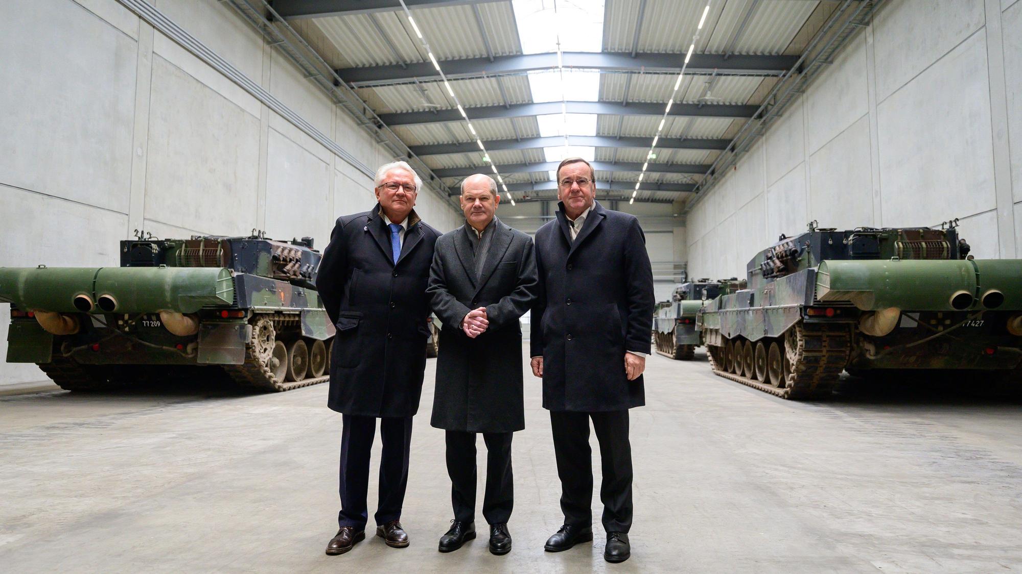 Armin Papperger (l-r), Vorstandsvorsitzender der Rheinmetall, Bundeskanzler Olaf Scholz (SPD), und Boris Pistorius (SPD), Bundesminister für Verteidigung, stehen in einer Halle mit Kampfpanzern vom Typ Leopard 2A4. Mit dem symbolischen Spatenstich auf dem Gelände von Rheinmetall wurde an dem Tag der Bau einer neuen Munitionsfabrik der Rheinmetall beginnen. In der Munitionsfabrik sollen Artilleriemunition, Explosivstoffe und Raketenartillerie produziert werden. Ein CNN-Bericht über angebliche russische Anschlagspläne gegen Rheinmetall-Chef Armin Papperger sorgt in Deutschland für Entrüstung.