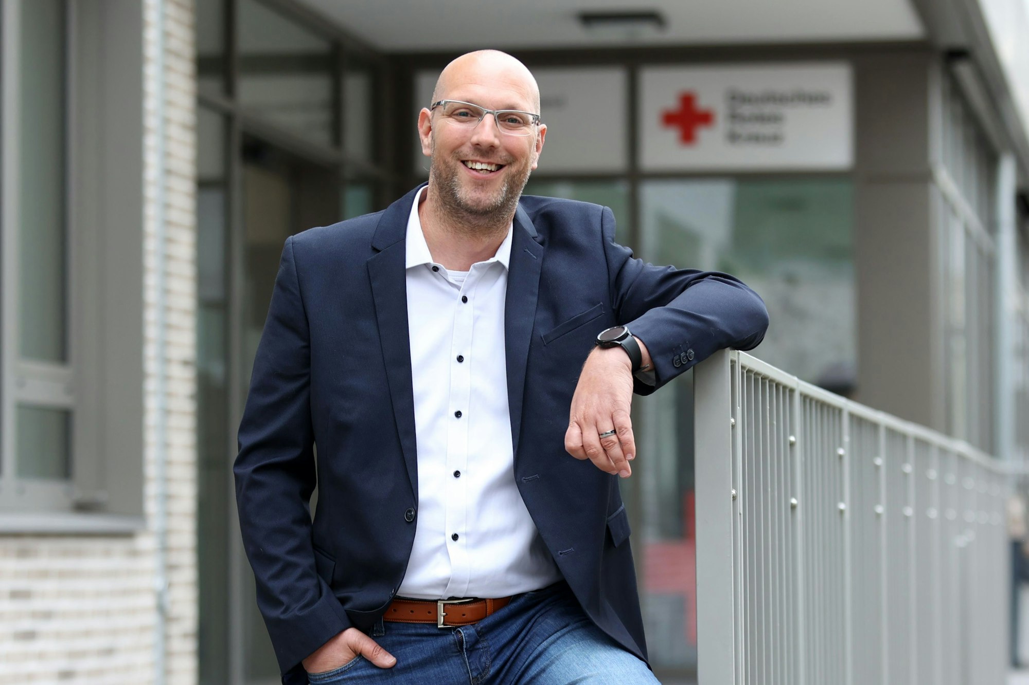 Marcel Pertsemlis, Bereichsleitung Hausnotruf, Fachbereich Senioren und Behinderte beim DRK, steht vor dem Gebäude des DRK in Köln Ehrenfeld.