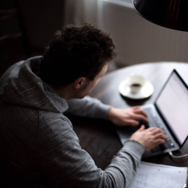 Ein Mann sitzt an einem Laptop und arbeitet. (gestellte Szene).