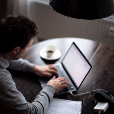 Ein Mann sitzt an einem Laptop und arbeitet. (gestellte Szene).