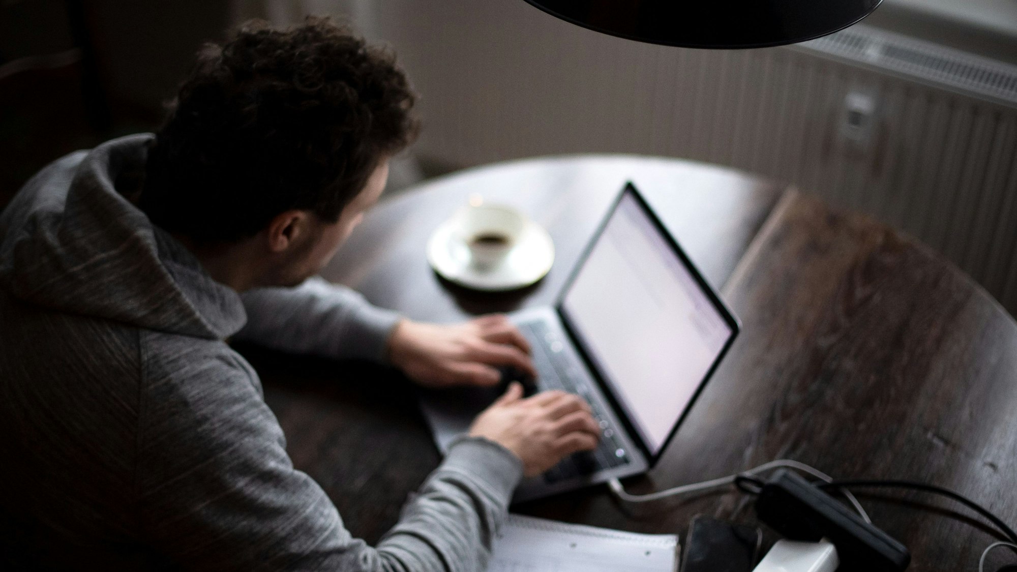 Ein Mann sitzt an einem Laptop und arbeitet. (gestellte Szene).