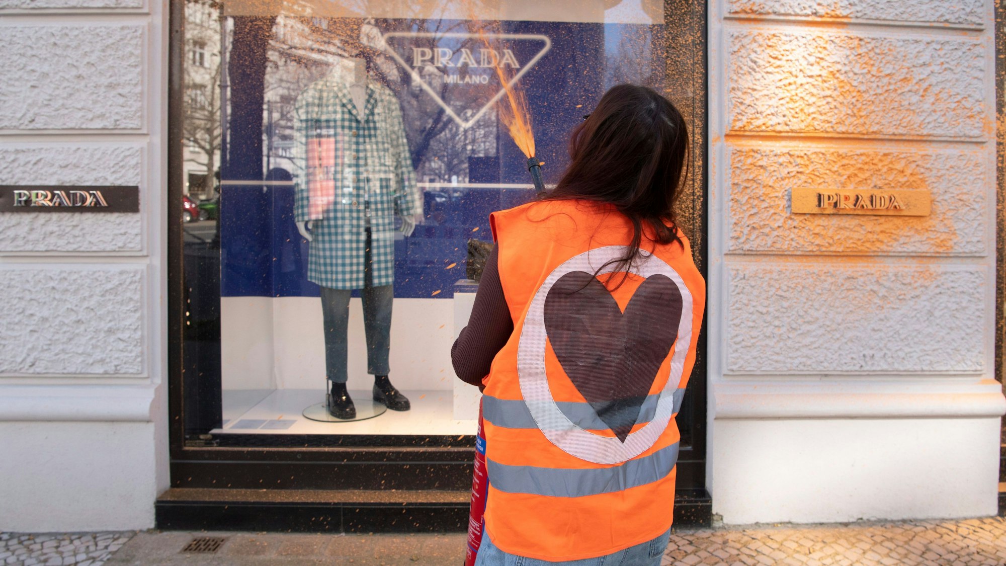 Eine Aktivistin der Umweltschutzgruppe Letzte Generation besprüht eine Fassade eines Luxusgeschäftes am Kurfürstendamm.