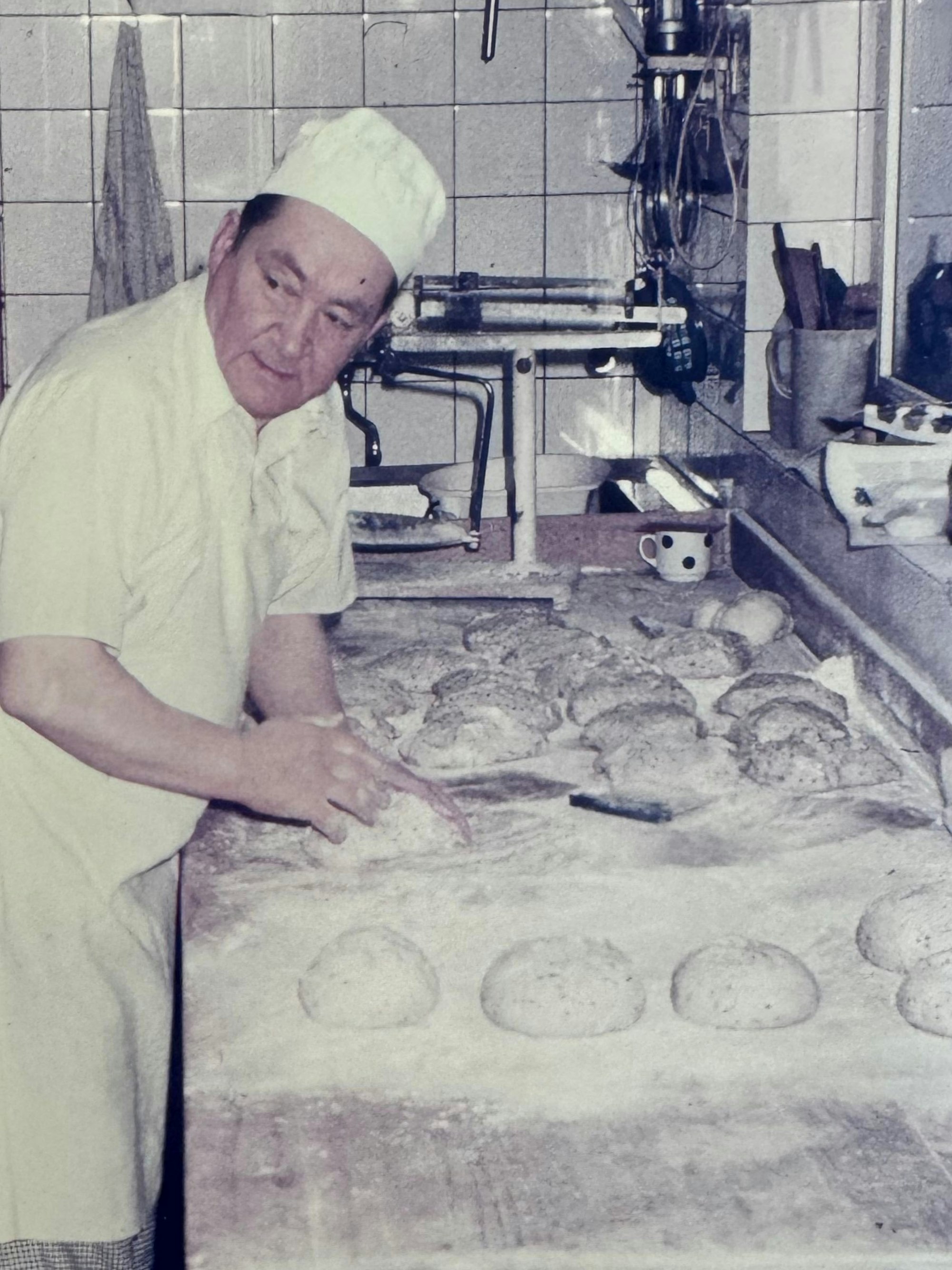 Ein Mann knetet in einer Backstube Teig