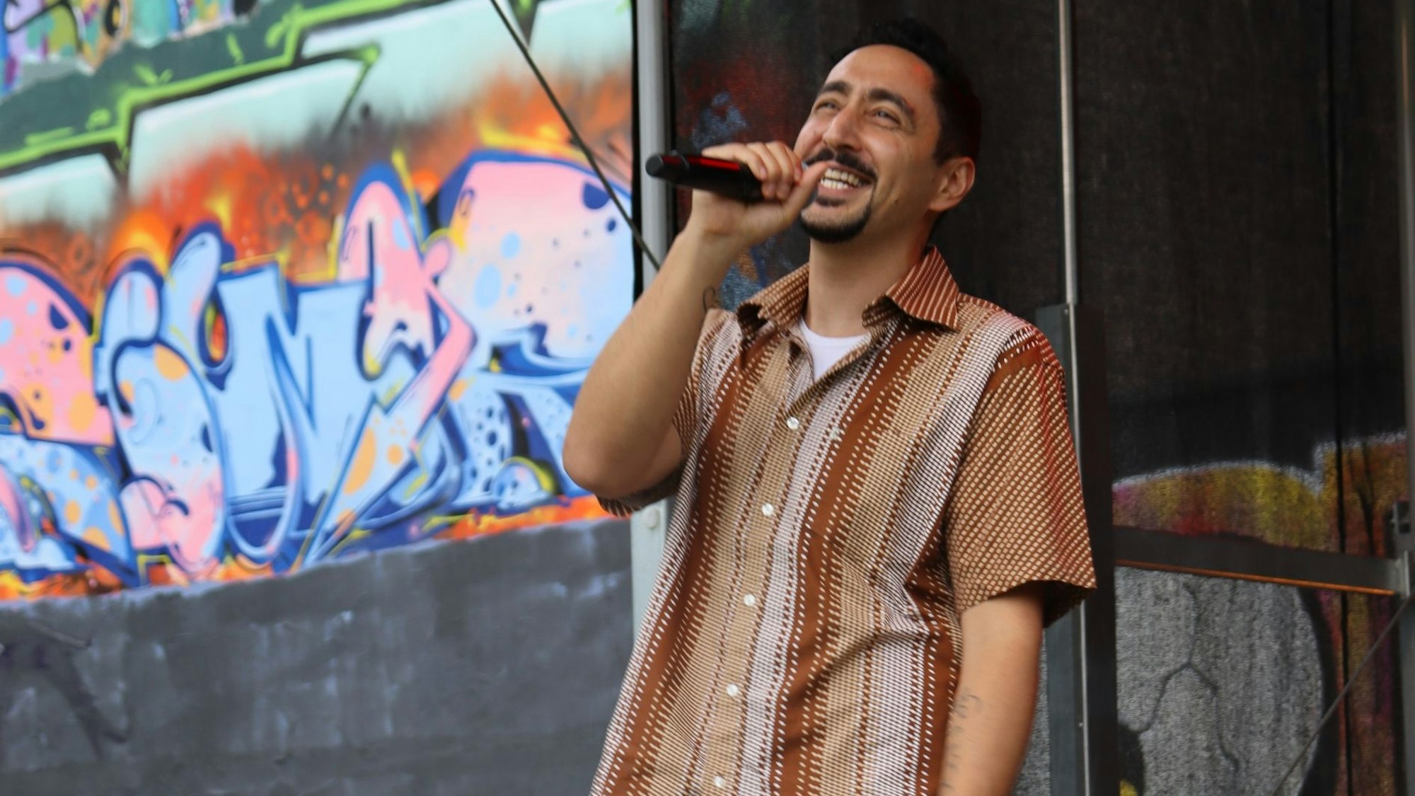 Zu sehen ist Eko Fresh mit Mikrofon in der Hand auf einer Bühne.