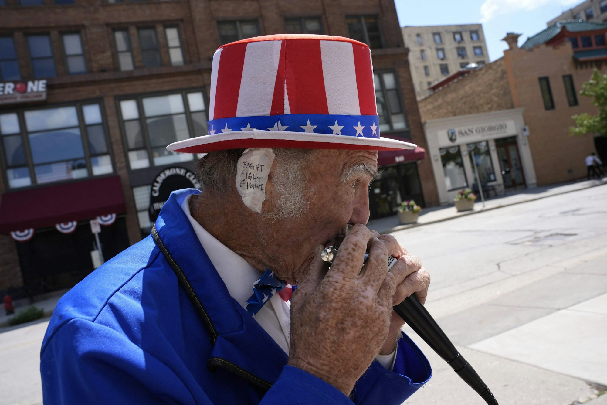 TOPSHOT - Duane Schwingel, dressed as Uncle Sam, plays harmonica  outside the Fiserv Forum during the third day of the 2024 Republican National Convention in Milwaukee, Wisconsin, on July 17, 2024. Days after he survived an assassination attempt Donald Trump won formal nomination as the Republican presidential candidate and picked Ohio US Senator J.D. Vance for running mate. (Photo by Nick Oxford / AFP)
