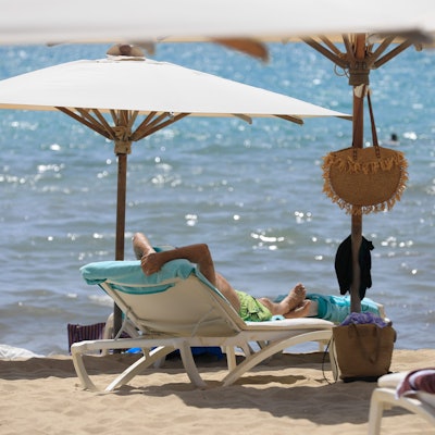 17.07.2024, Spanien, Palma: Menschen sonnen sich am Strand von Arenal und baden im Meer an einem warmen Sommertag. Foto: Clara Margais/dpa +++ dpa-Bildfunk +++