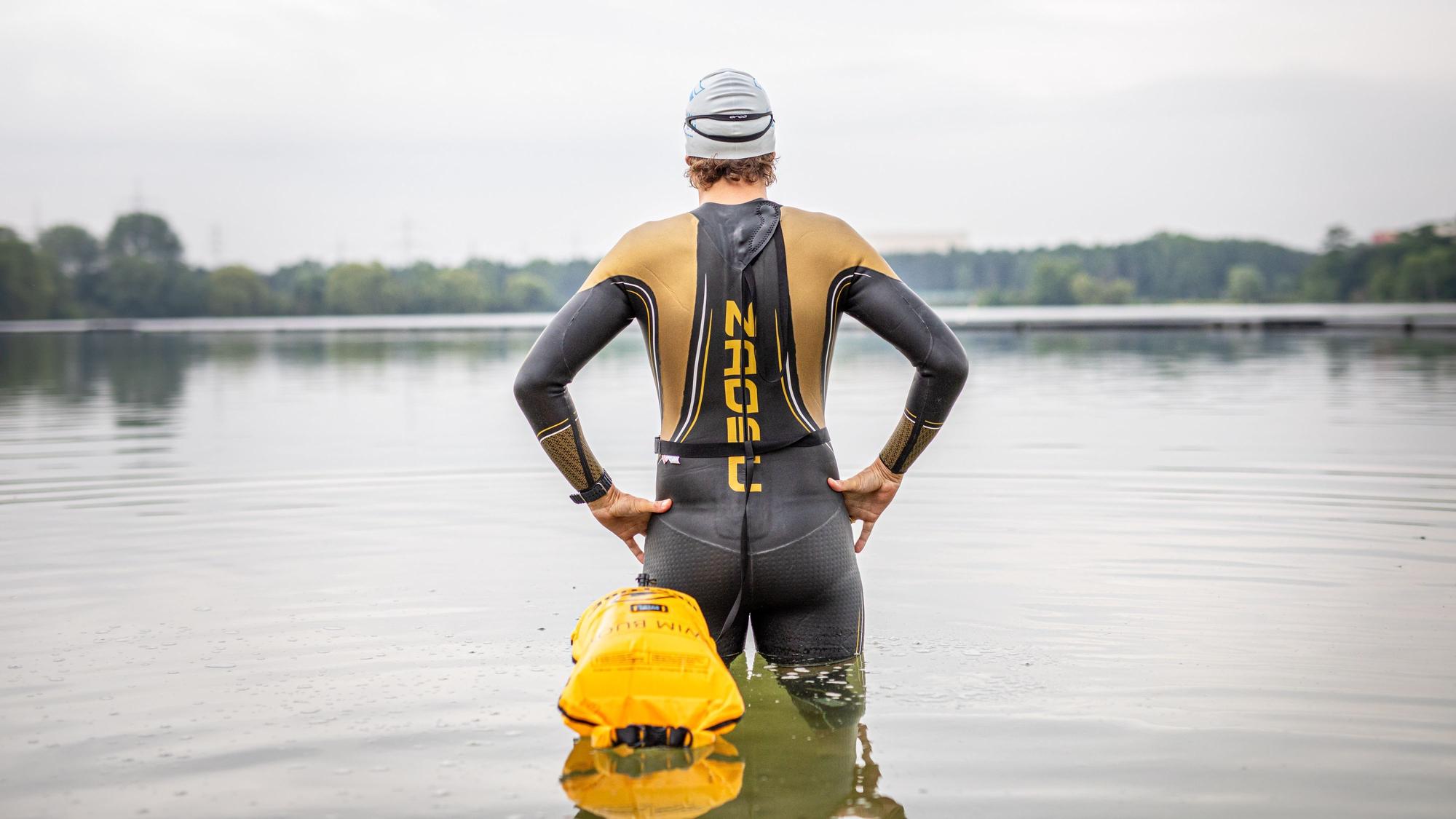 Der Schwimmtrainer und Athlet Johann Ackermann steht im Wasser am Ufer des Fühlinger See. Ackermann gibt unter dem Namen „Der Schwimmcoach“ regelmäßig Workshops für Triathleten, bei denen es um das Freiwasserschwimmen geht.