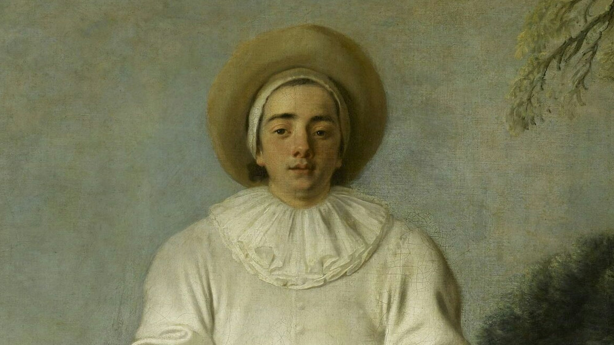 Ein junger Mann im weißen Clownskostüm blickt uns an.