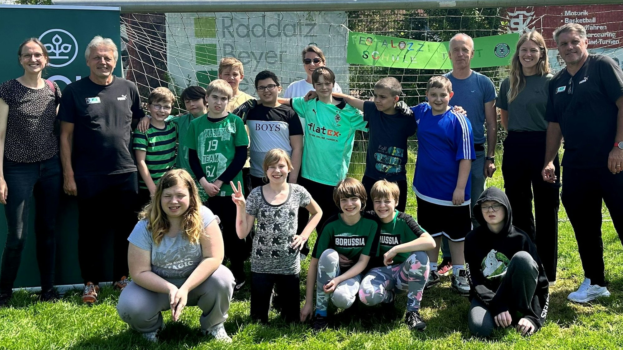 Zu sehen ist ein Gruppenbild mit den einstigen Fußballprofis und den Schülern.