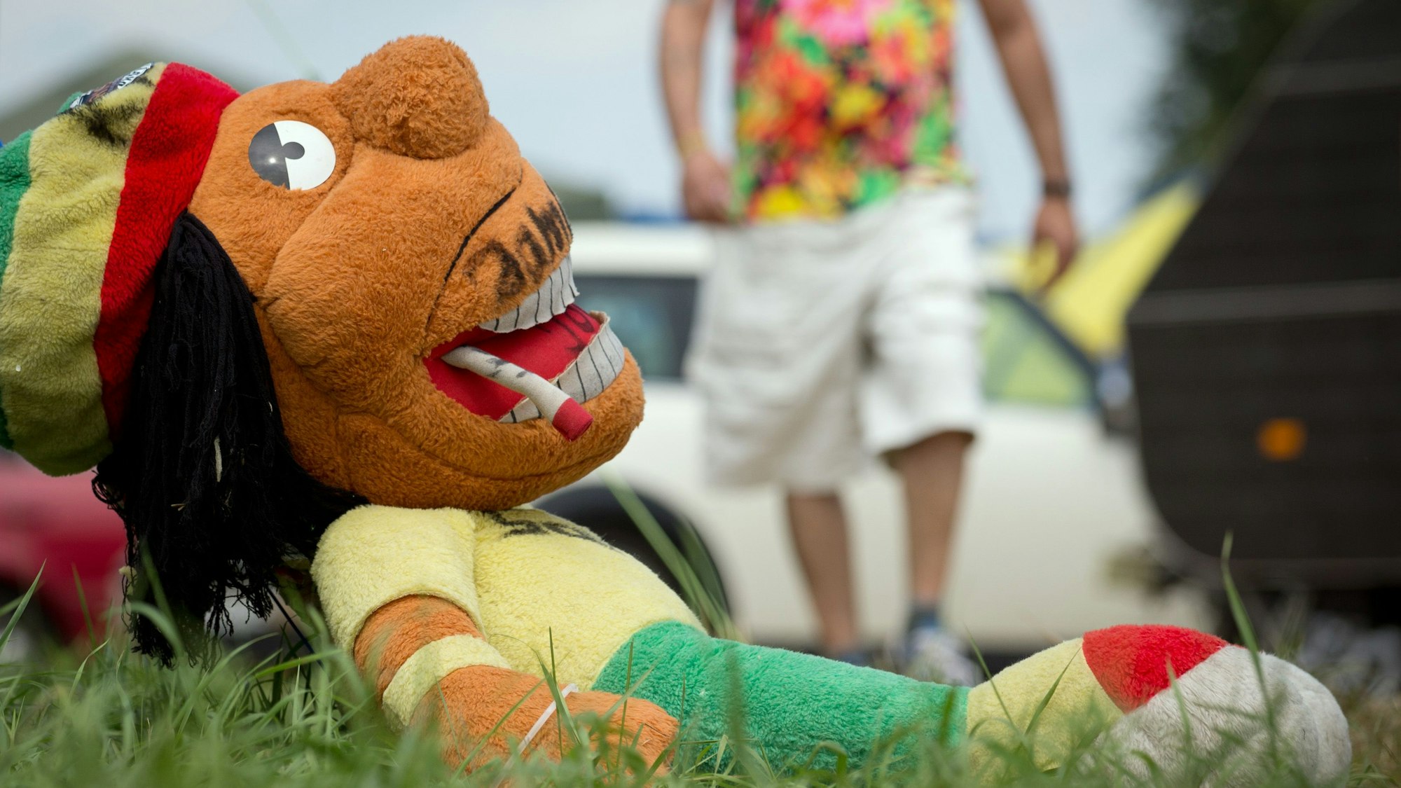 Eine "kiffende" Puppe liegt auf dem Gras.