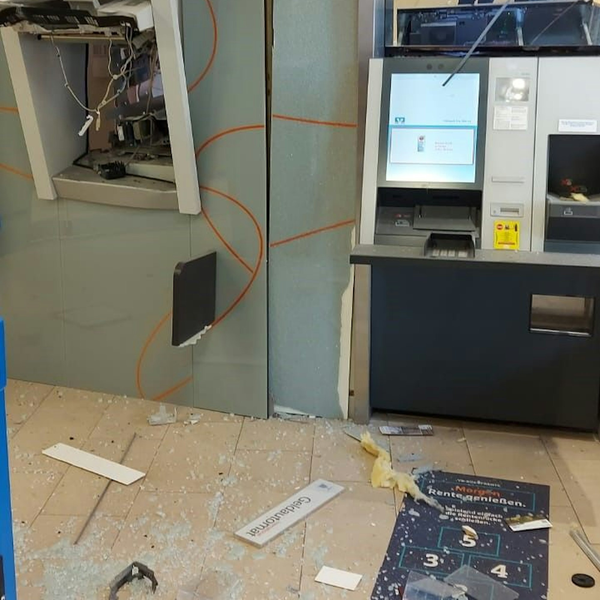 Im Vorraum der Volksbank in Hillesheim liegen Glassplitter auf dem Boden, der Geldautomat (l.) befindet sich nicht mehr in seiner Halterung.
