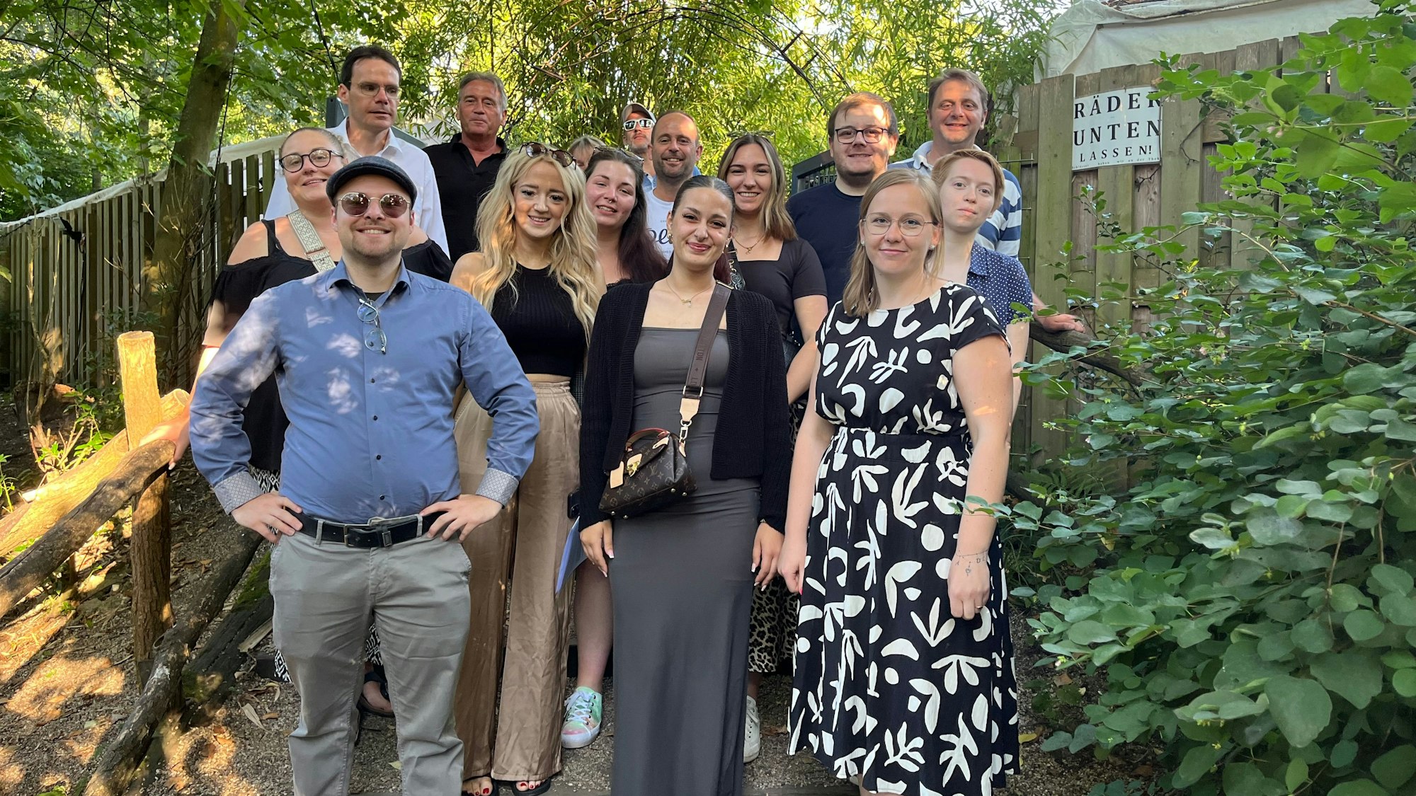 Die Absolventen des Bachelor Professionals in Wirtschaft des Berufskolleg Eifel stehen auf einer Treppe vor ienem Zaun, rundherum sind Bäume zu sehen.