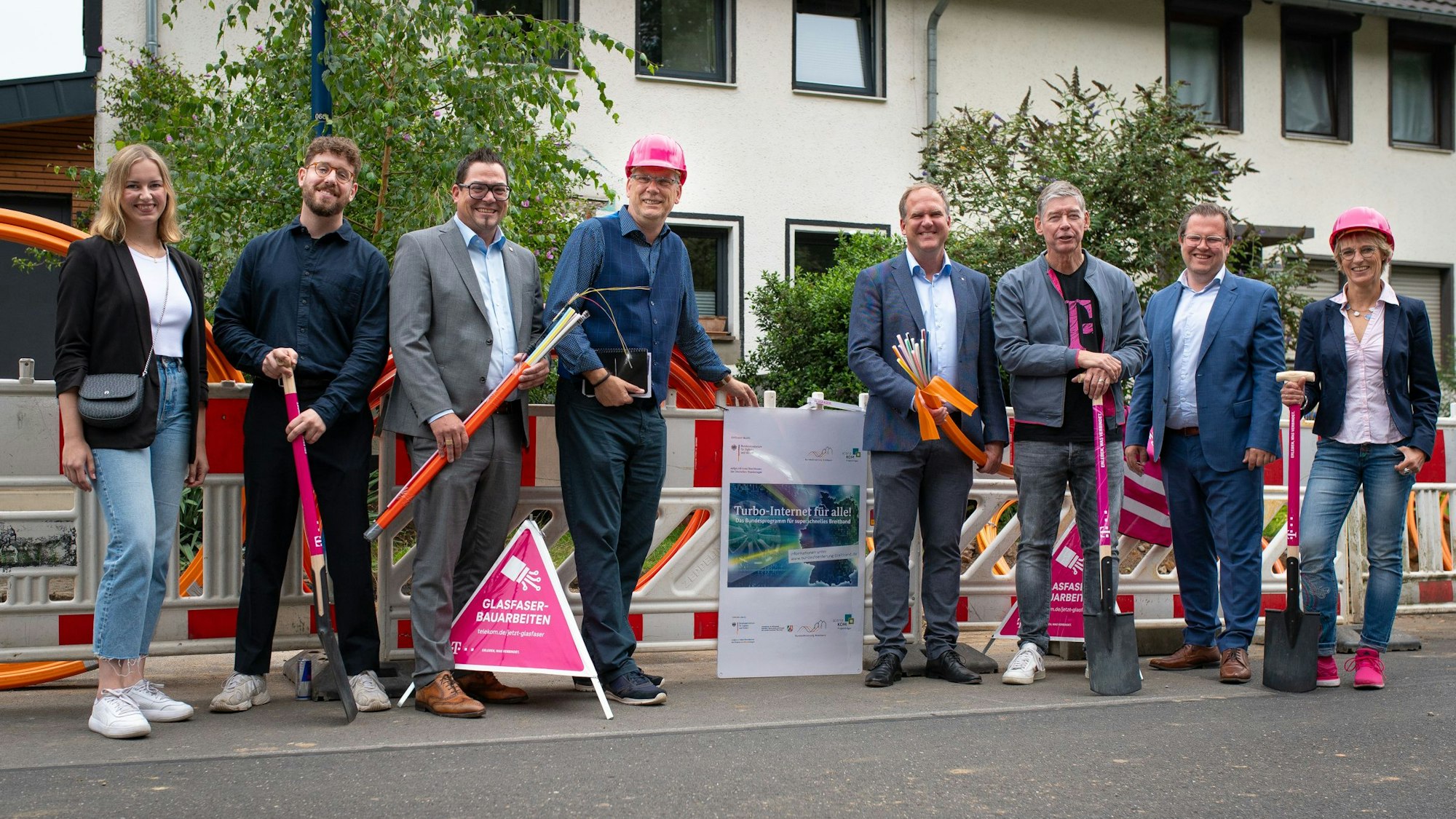 Männer und Frauen stehen vor einer Baustelle.