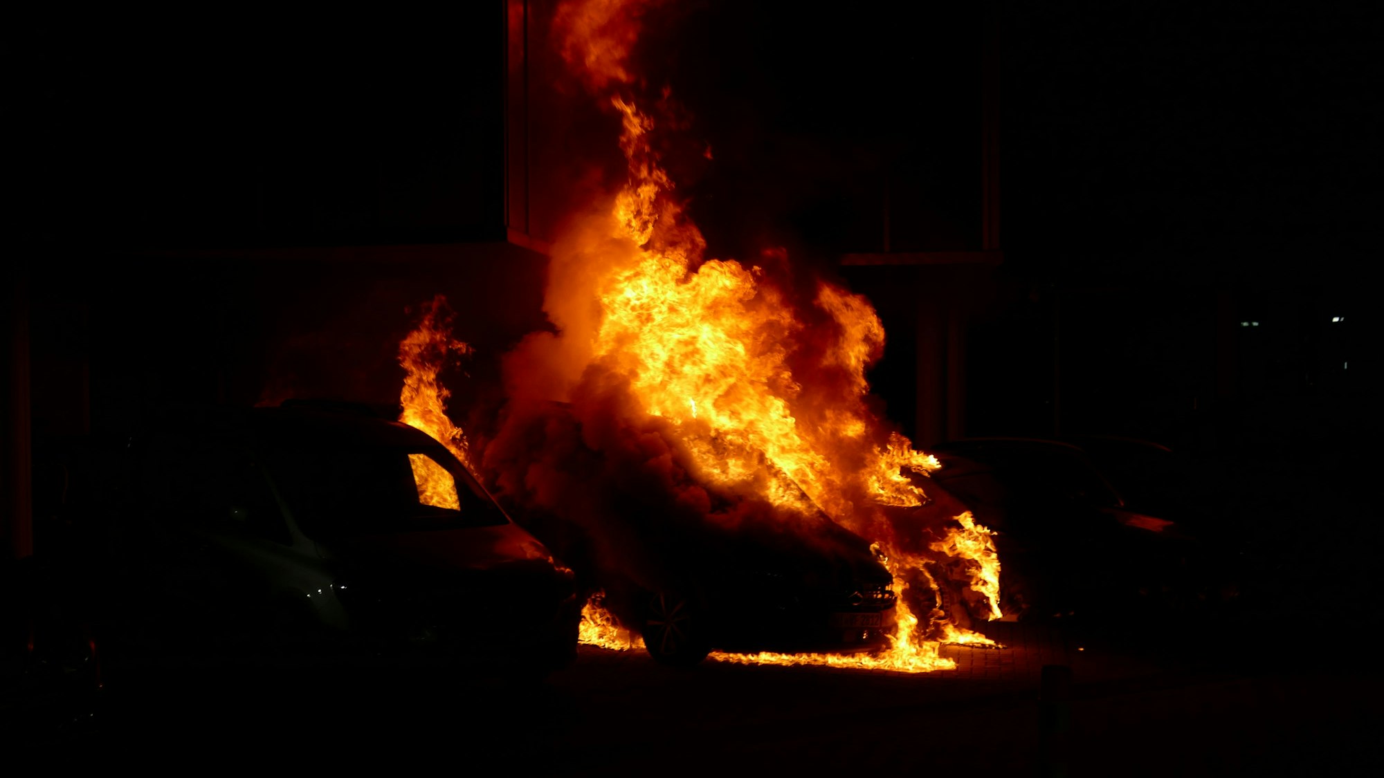 Ein Auto brennt in der Dunkelheit.
