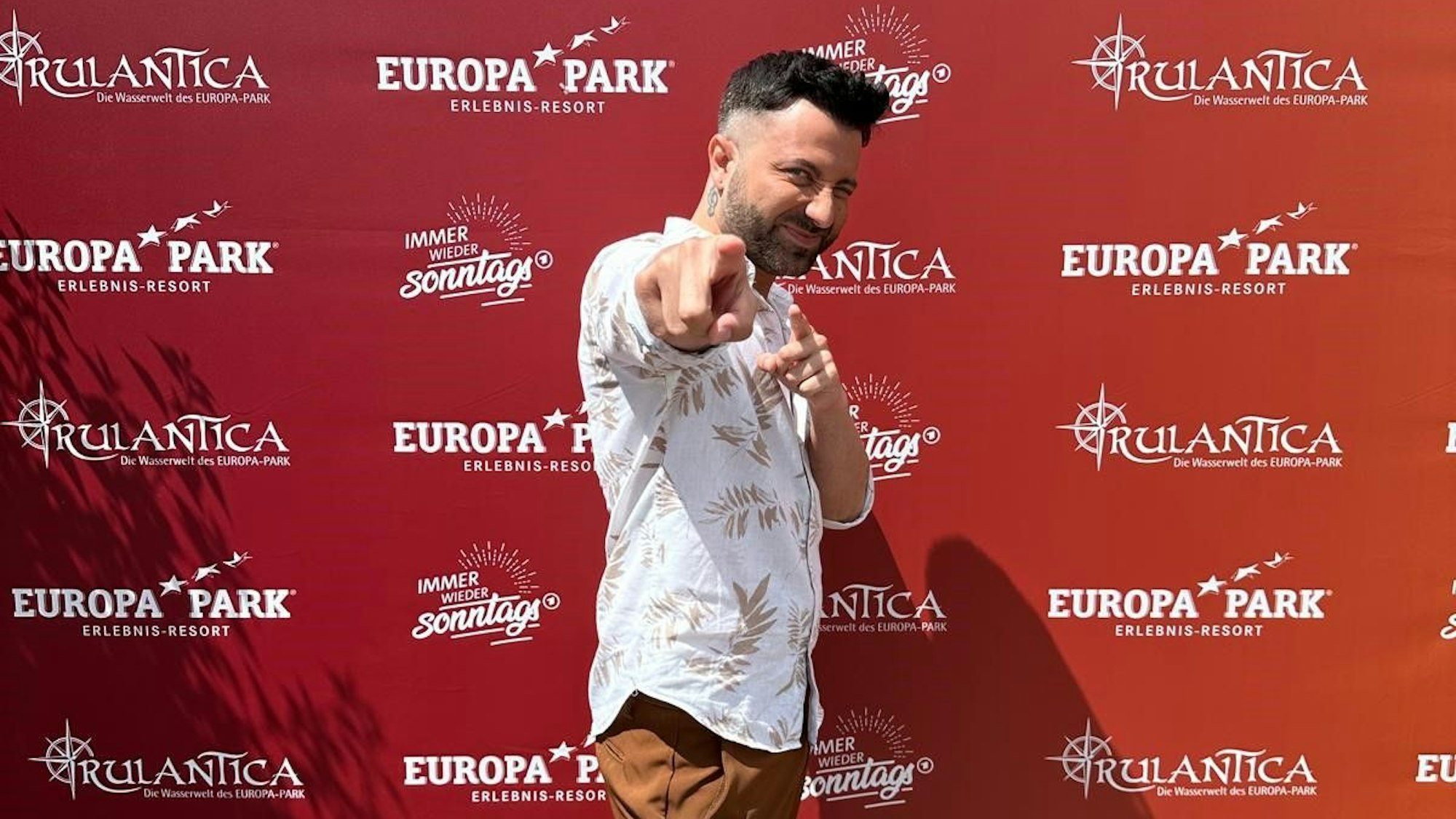 Nico Alesi posiert vor einer roten Wand.