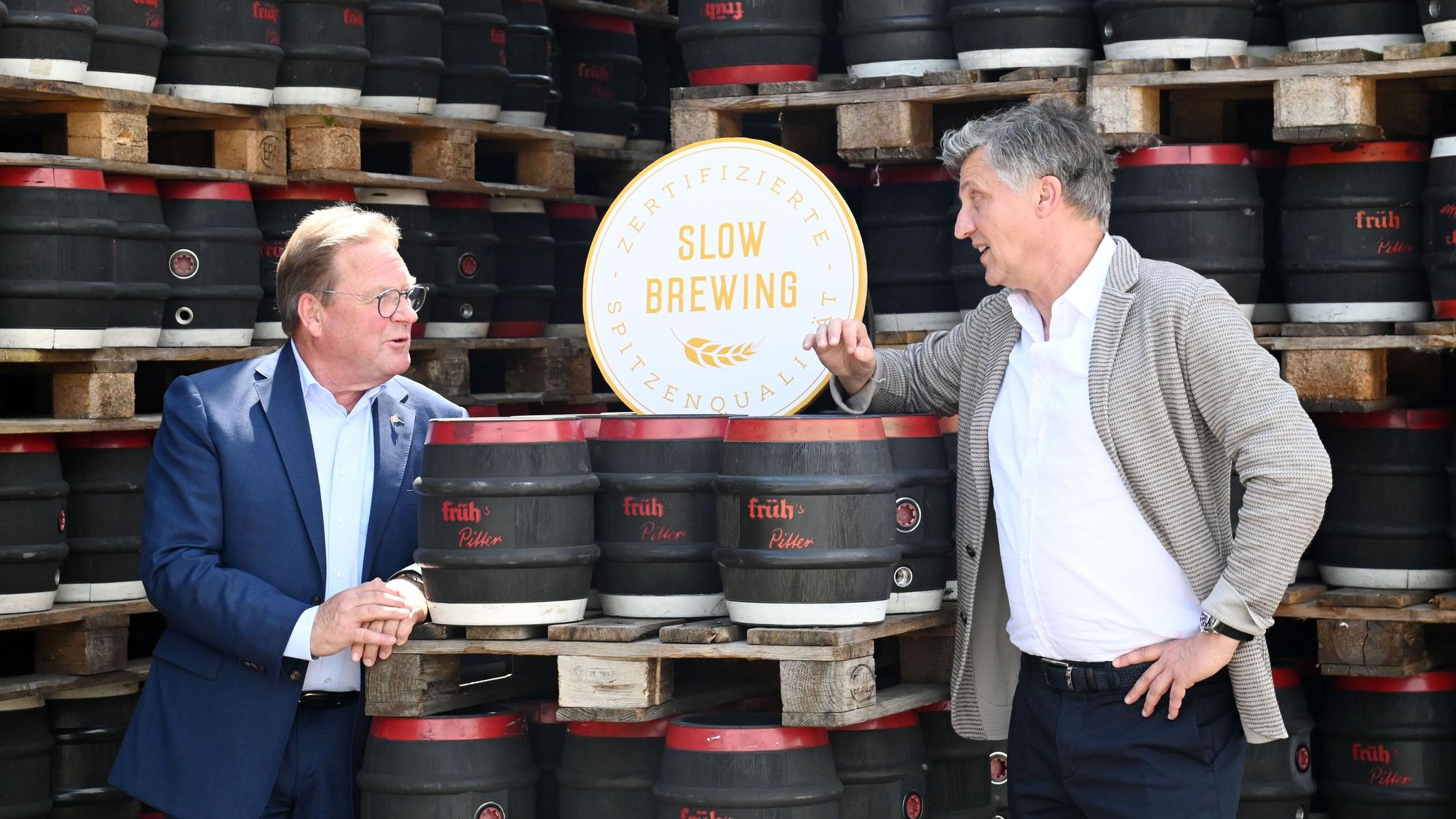 August Gresser und Dirk Heisterkamp unterhalten sich vor Bierfässern.