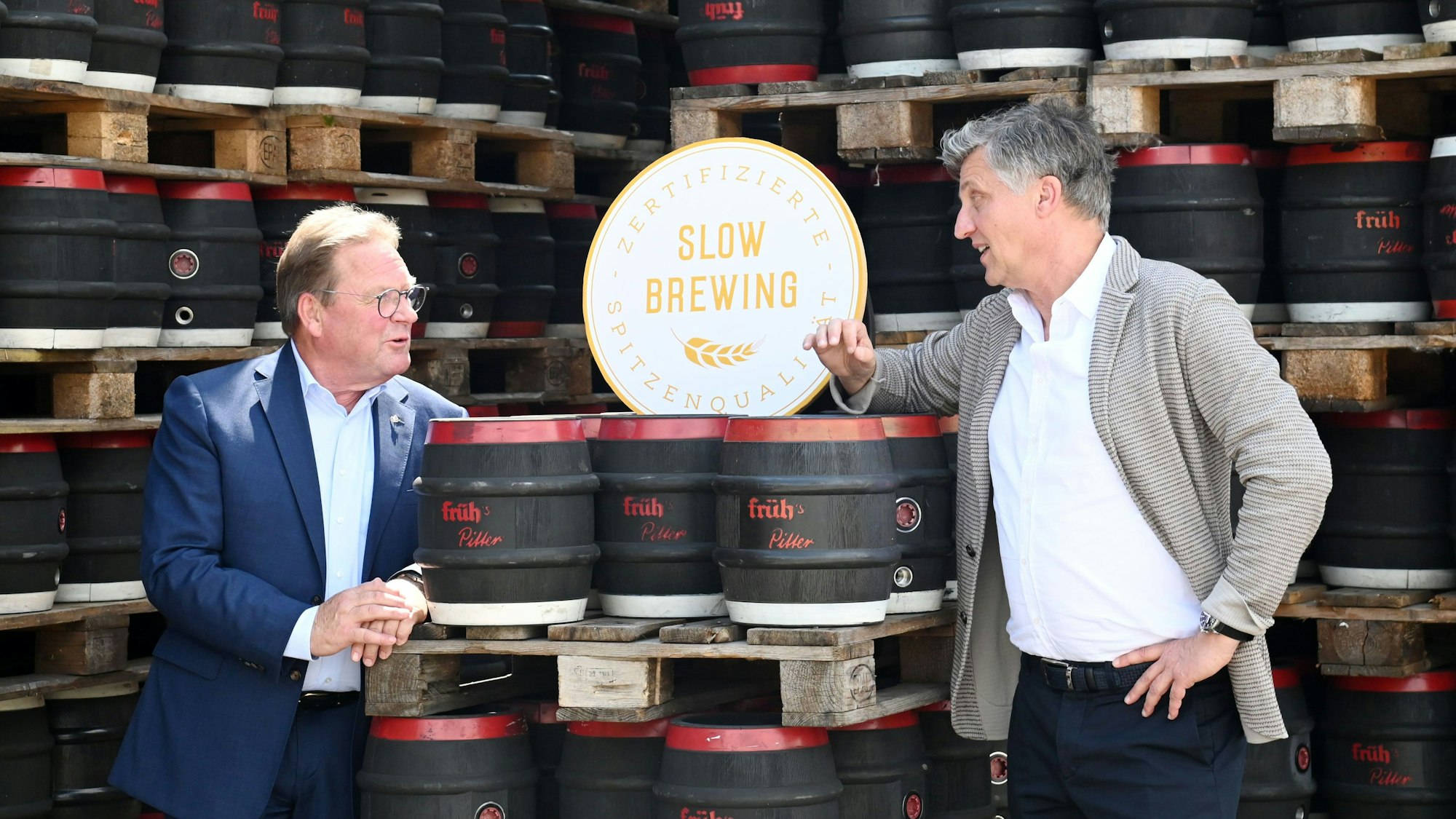 August Gresser und Dirk Heisterkamp unterhalten sich vor Bierfässern.