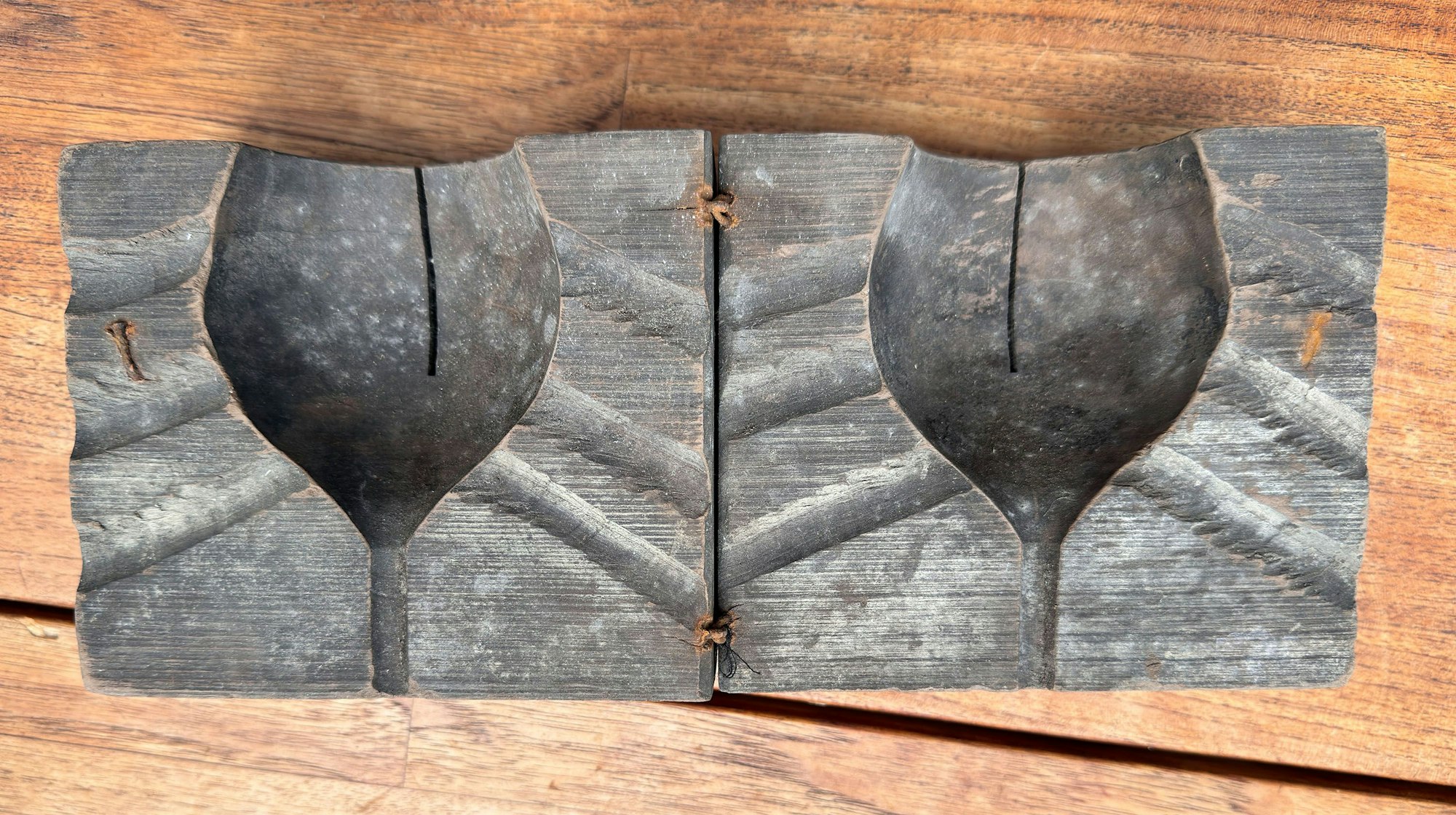 Zu sehen ist eune Form aus Holz, mit der ein Glas in Form geblasen wird.