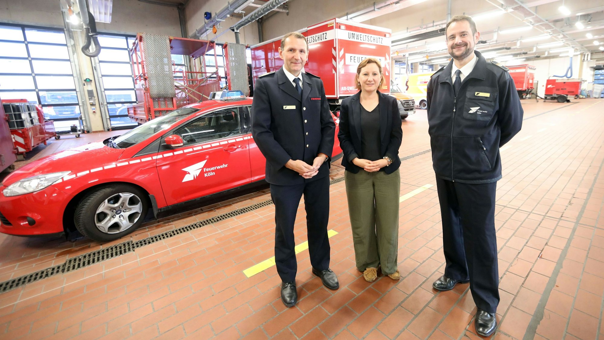 Kölns Feuerwehrchef Christian Miller, der Leiter des Forschungsinstituts Stefan Martini (r.) und Wissenschaftlerin Angelika Schweimnitz in der Wagenhalle der Feuerwache in Weidenpesch