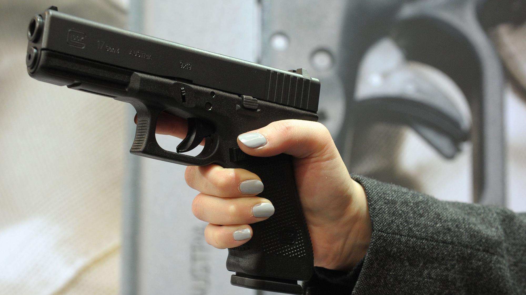 Eine Frauenhand hält eine eine halbautomatische Pistole.
