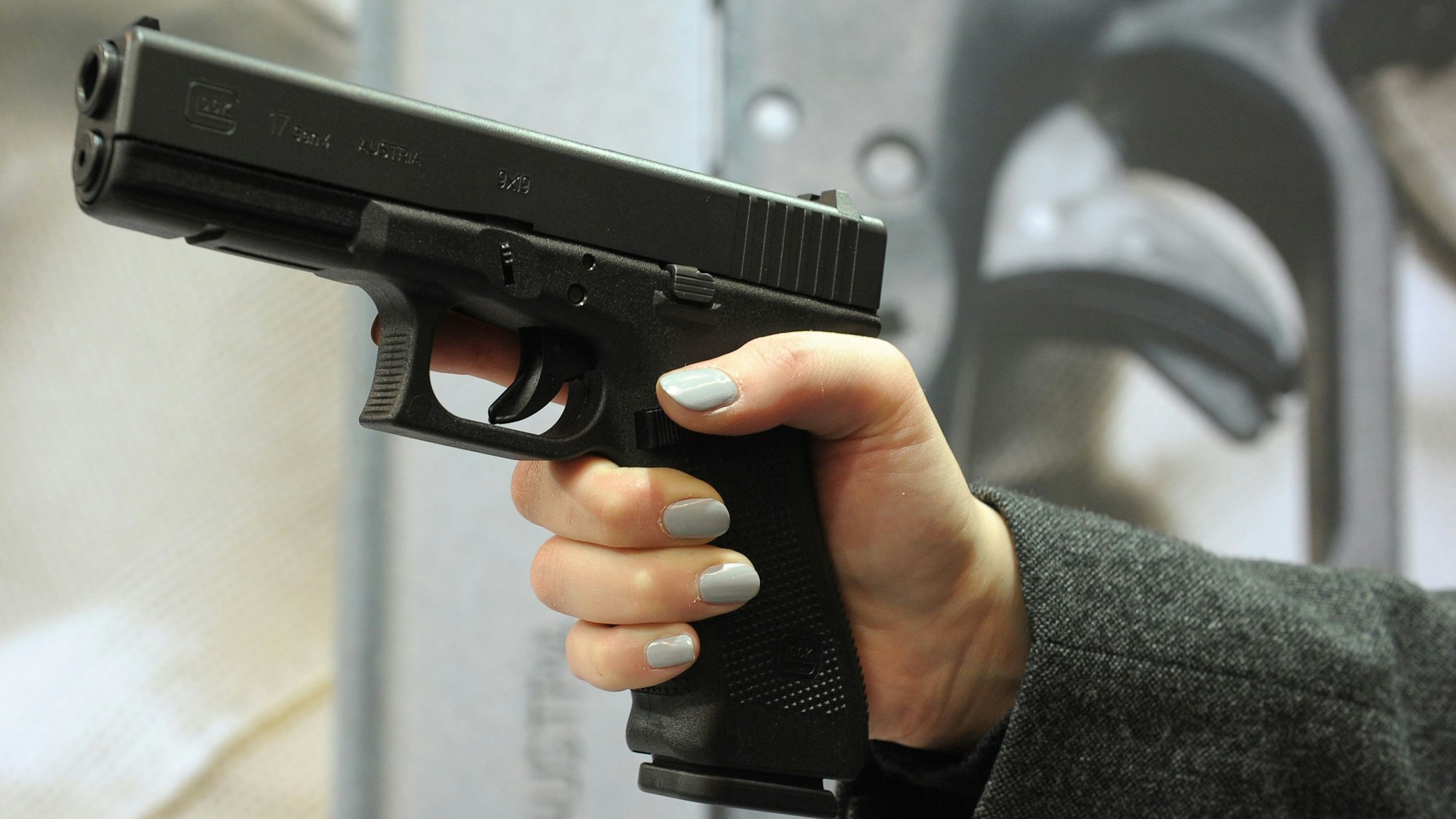 Eine Frauenhand hält eine eine halbautomatische Pistole.
