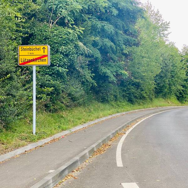 Auf dem Ortsausgangsschild von Lützenkrichen in der Altenberger Straße ist das Wort Lützenkrichen durchgestrichen. Der Anfang von Steinbüchel wird in einem Kilometer gekennzeichnet.