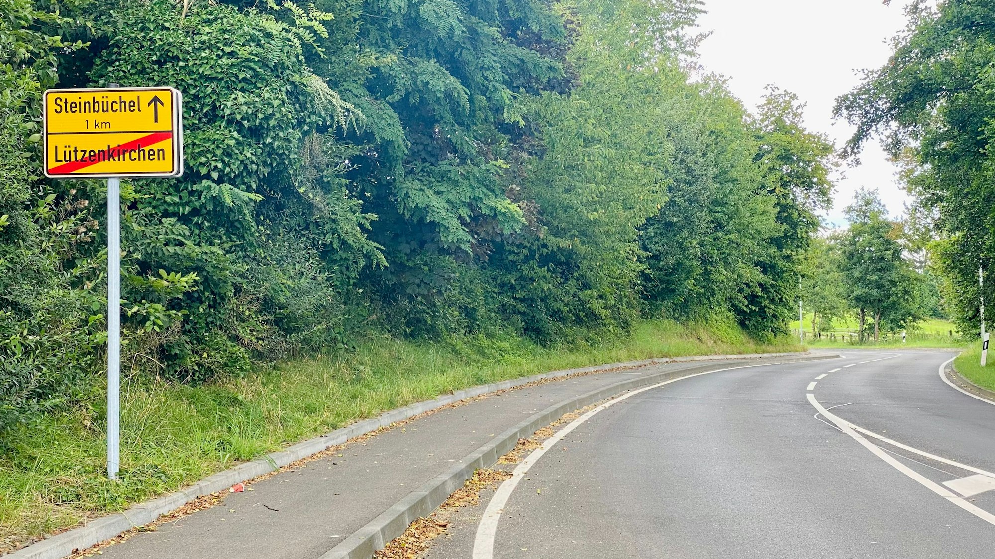 Auf dem Ortsausgangsschild von Lützenkrichen in der Altenberger Straße ist das Wort Lützenkrichen durchgestrichen. Der Anfang von Steinbüchel wird in einem Kilometer gekennzeichnet.