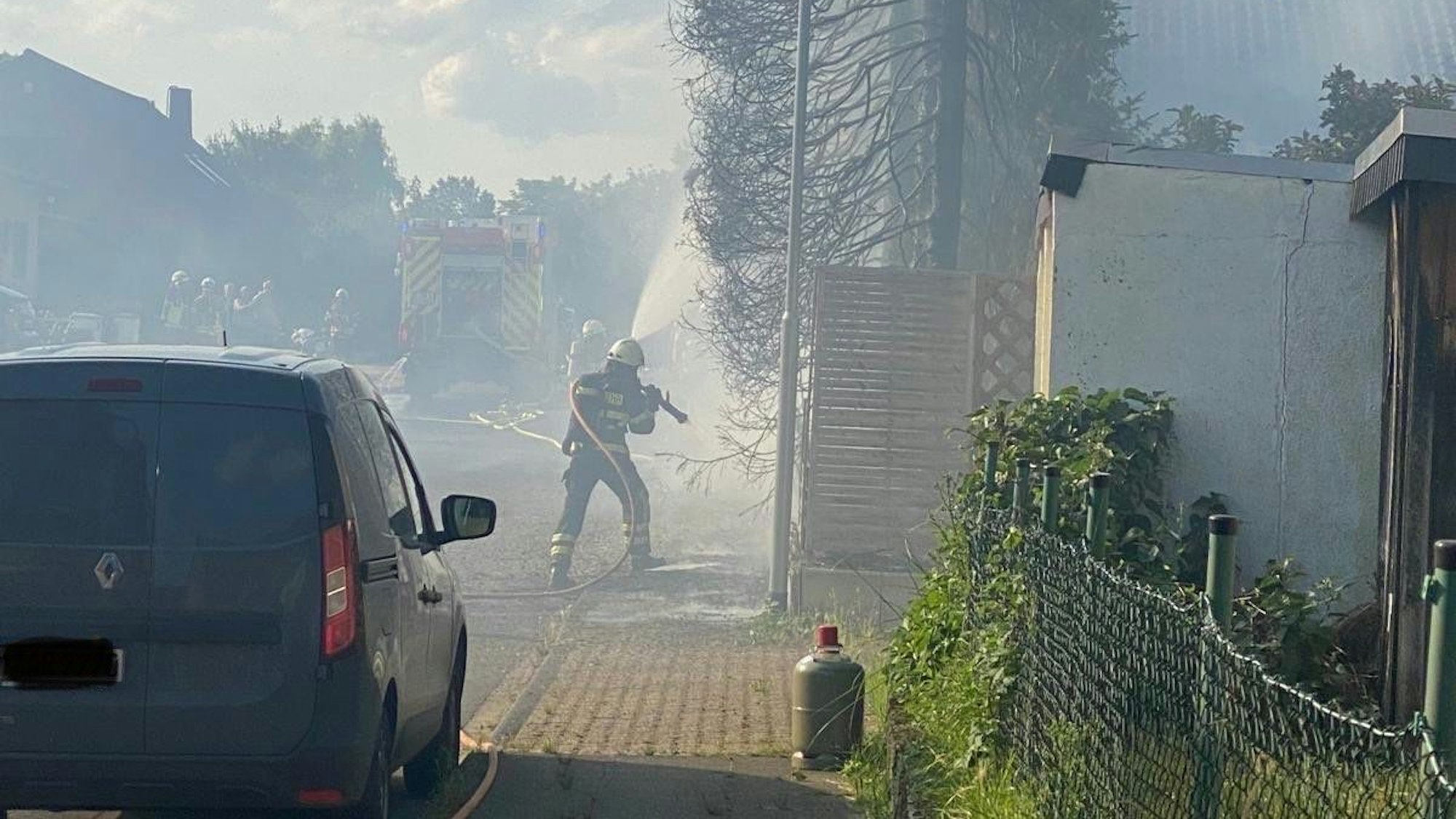 Ein Feuerwehrmann löscht einen Brand an einer Hecke.