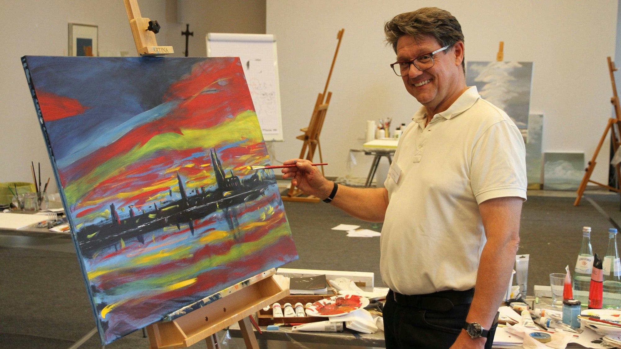 Ein Mann an einer Staffelei mit einer Ansicht von Köln